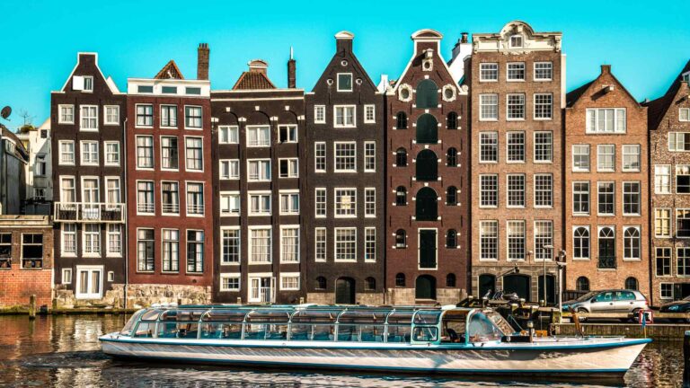 Tall narrow canal houses reflected in Amsterdam water