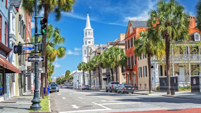 Historic Charleston street lined with palm trees and a white church steeple