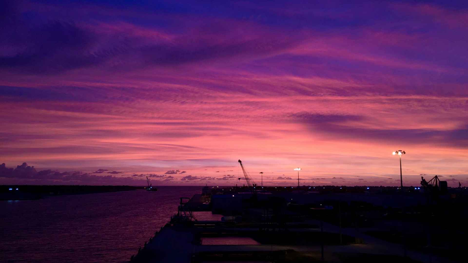 Port Canaveral silhouetted beneath a vivid purple and orange sunset