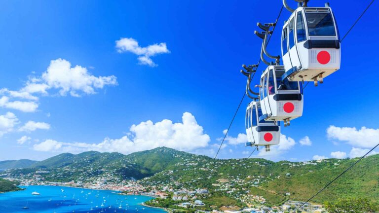 Aerial tram cars traveling above Charlotte Amalie under a vivid blue sky