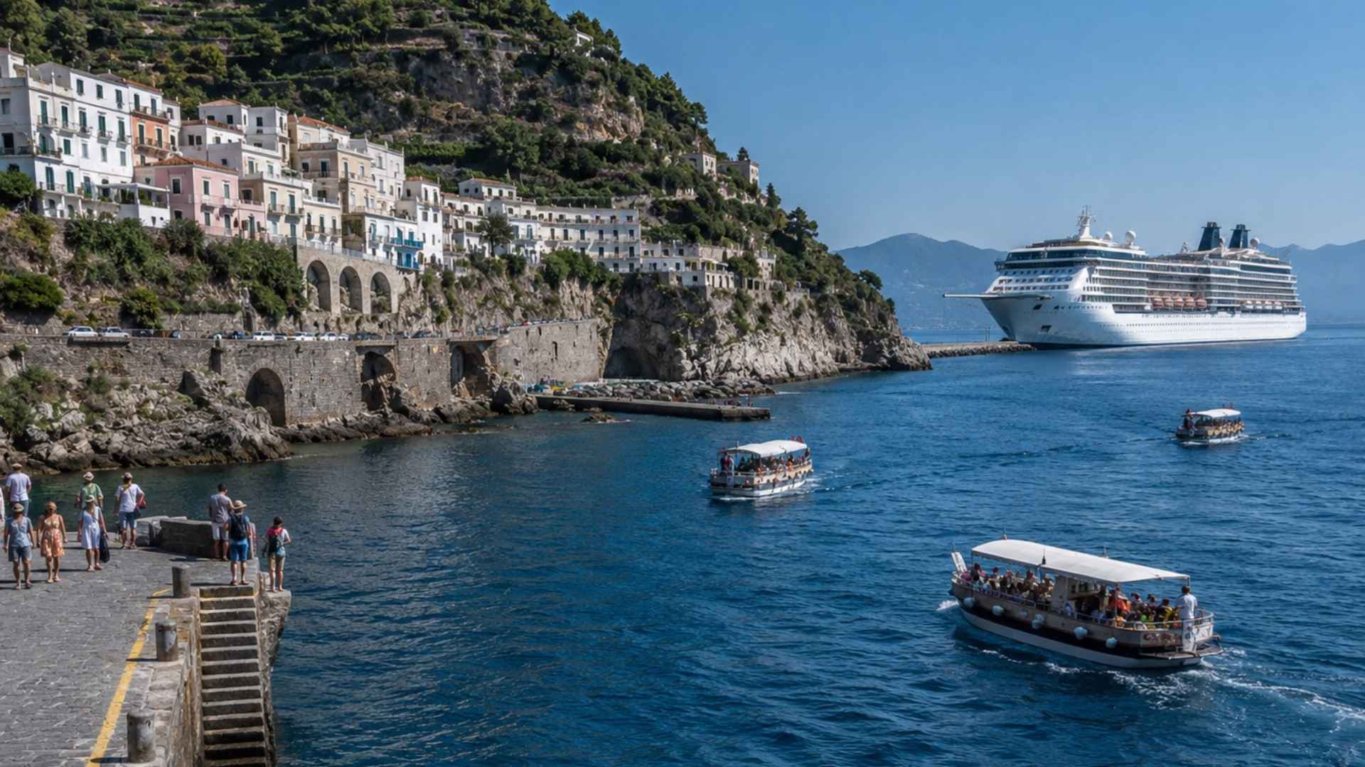 Cruise tender boats crossing blue water toward a Mediterranean cliffside town