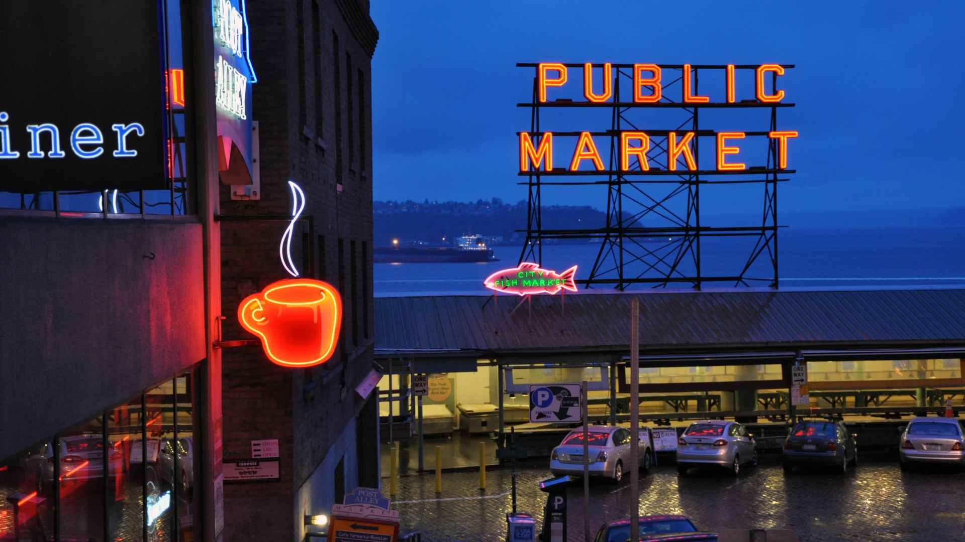 Pike Place Market sign glowing above the Seattle waterfront at night
