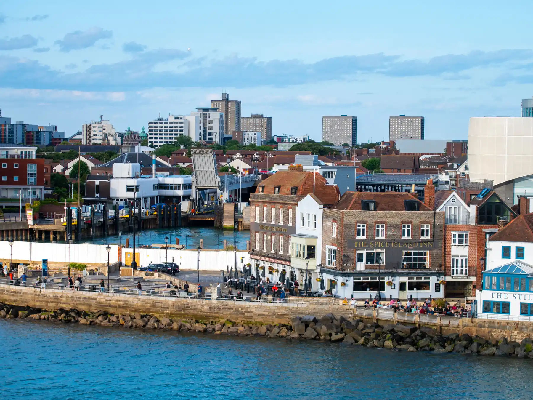 Portsmouth Harbor waterfront with historic buildings, city skyline, and blue coastal water.