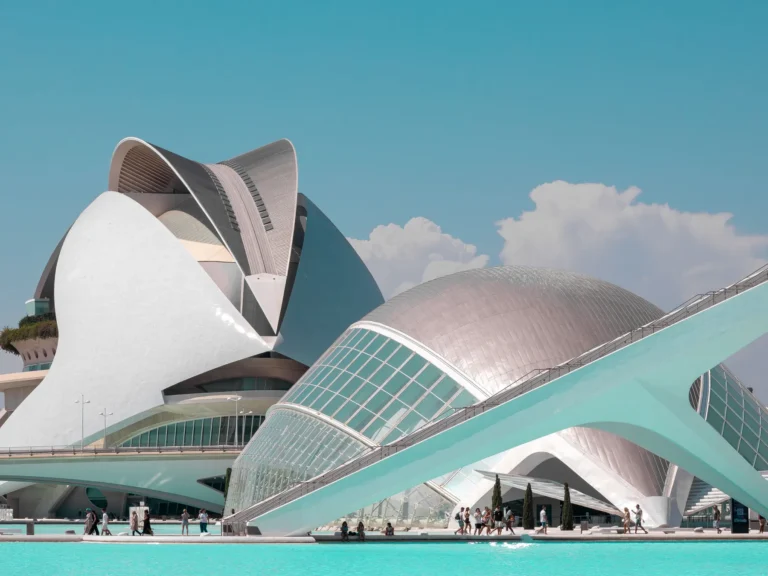 Valencia's City of Arts and Sciences beside turquoise reflecting pools under a clear blue sky.