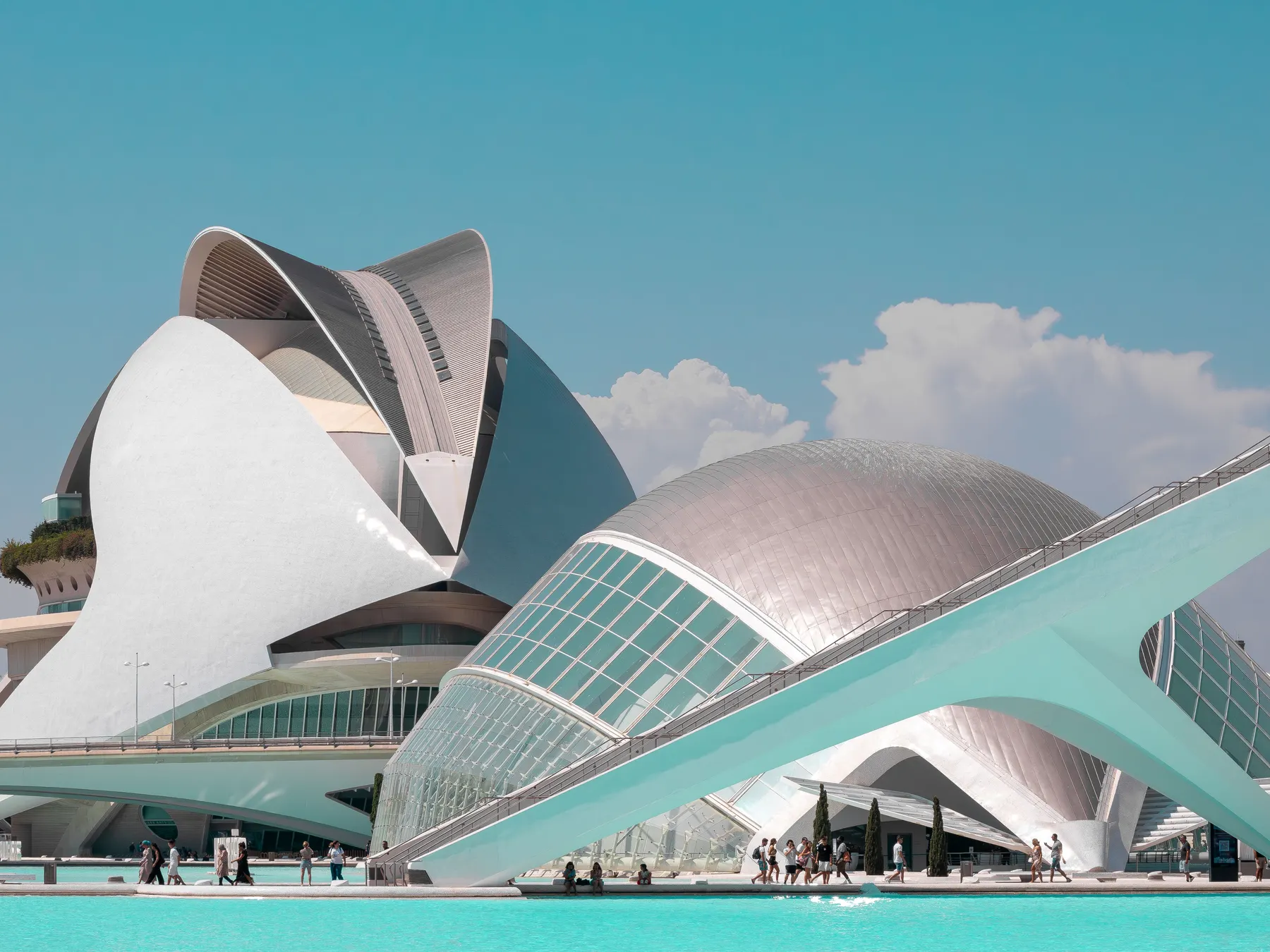 Valencia's City of Arts and Sciences beside turquoise reflecting pools under a clear blue sky.