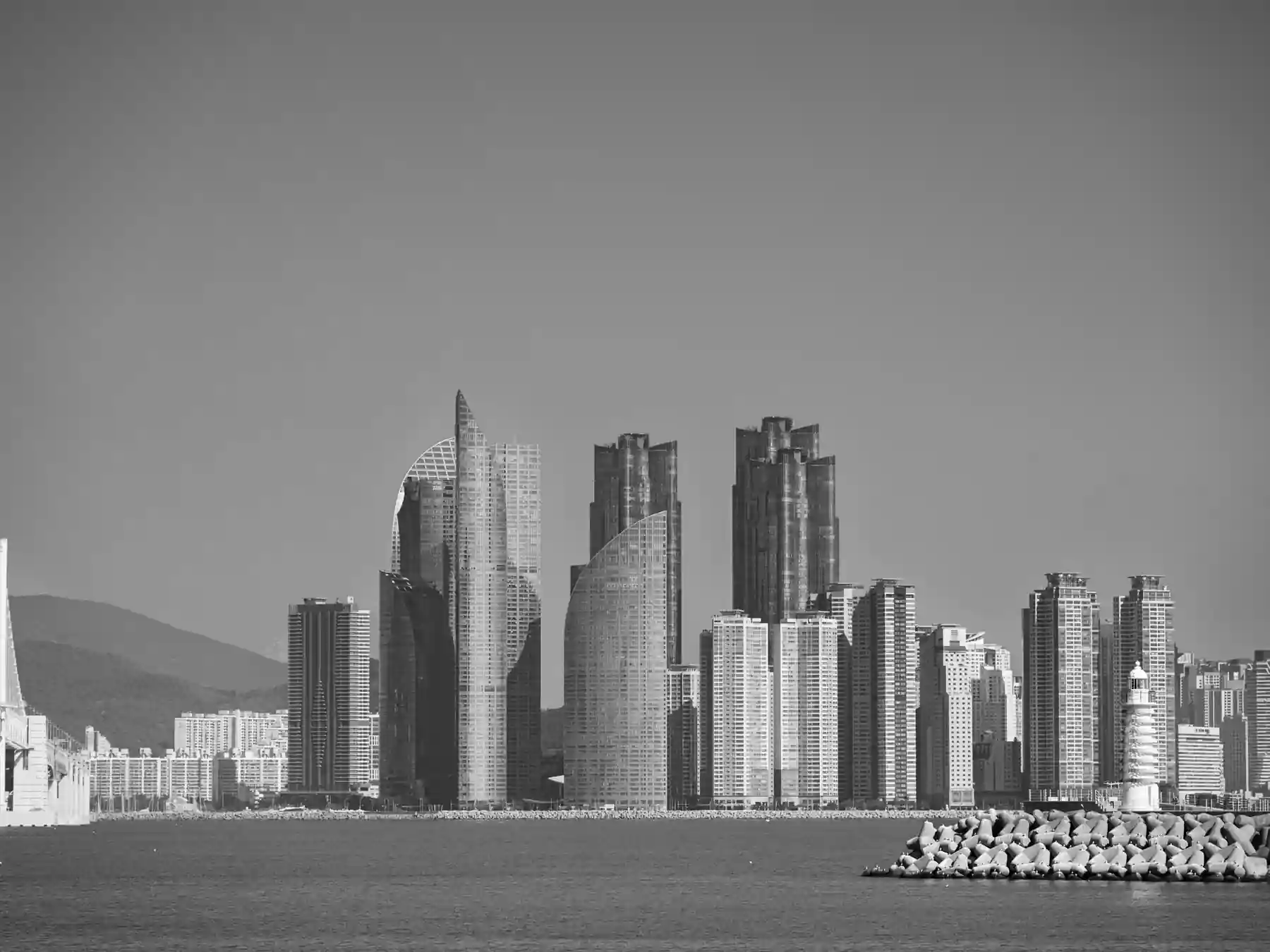 Busan skyline and harbor breakwater viewed across the water.