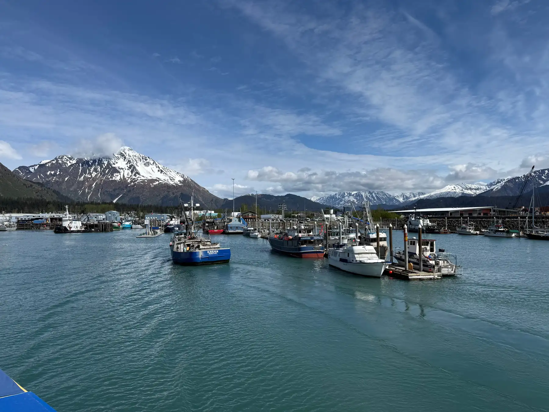 Fishing boats in Seward Boat Harbor with snow-covered mountains behind the marina.