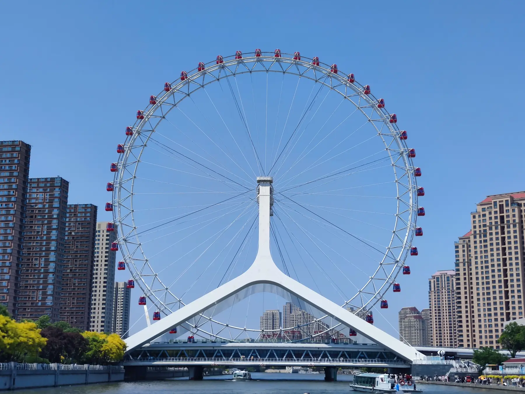 Tianjin Eye Ferris wheel spanning the Haihe River with city buildings behind it.