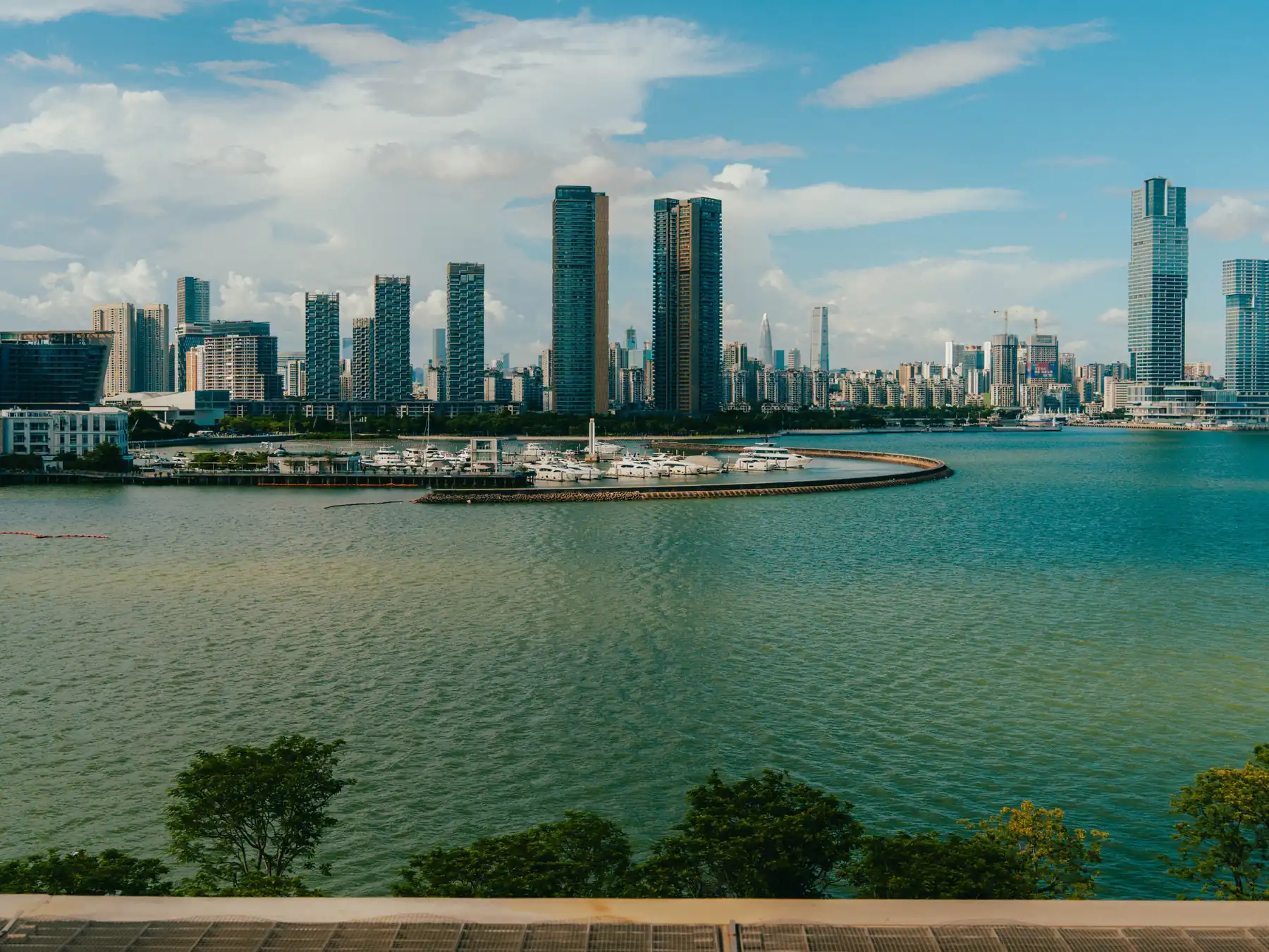 Wide view of high-rise buildings and marina water along Shenzhen Bay.