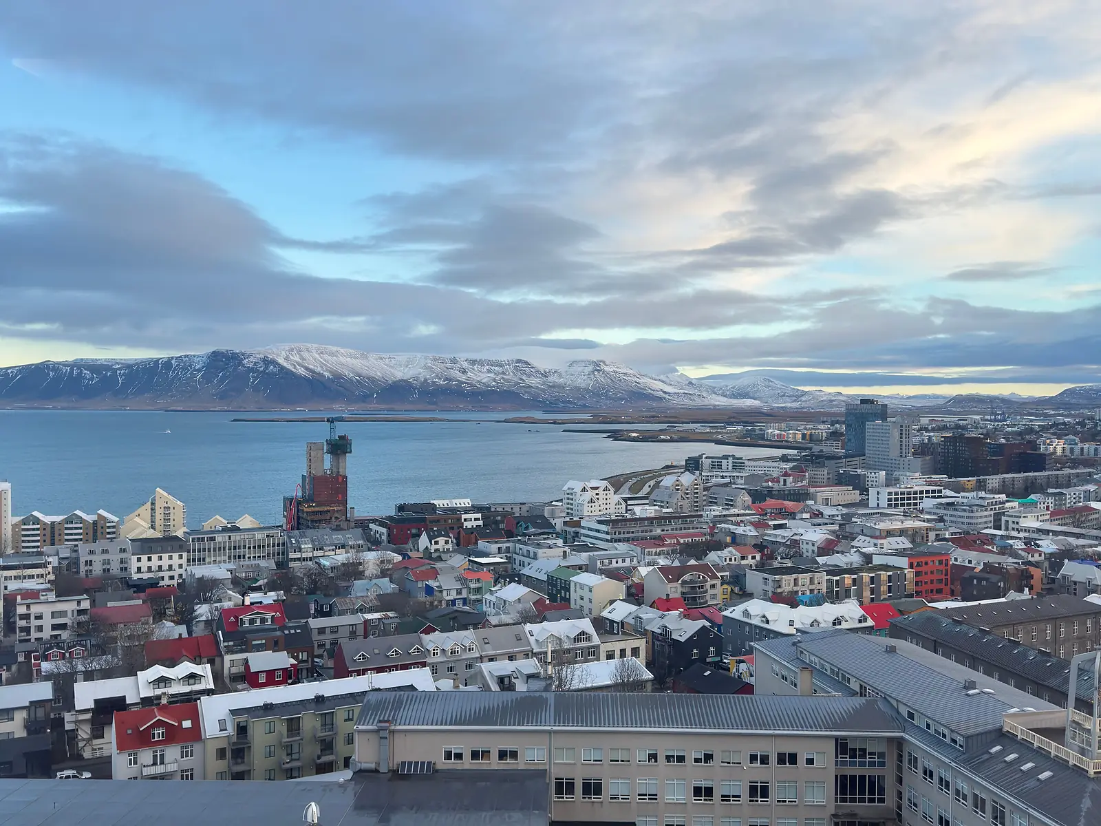 Aerial view of Reykjavík with colorful rooftops, ocean, and snowy mountains