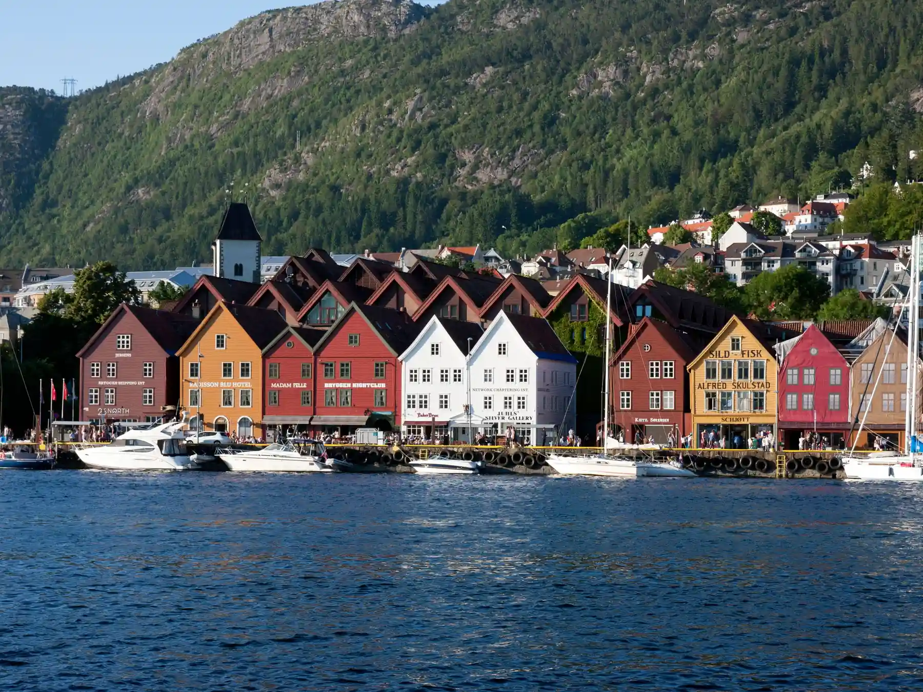 Bergen's waterfront with colorful buildings, boats, and green mountains in the background.