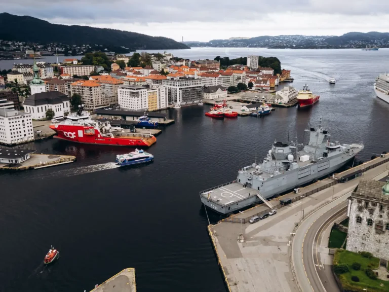 Aerial view of Bergen harbor with ships, waterfront buildings, and surrounding hills in Norway.