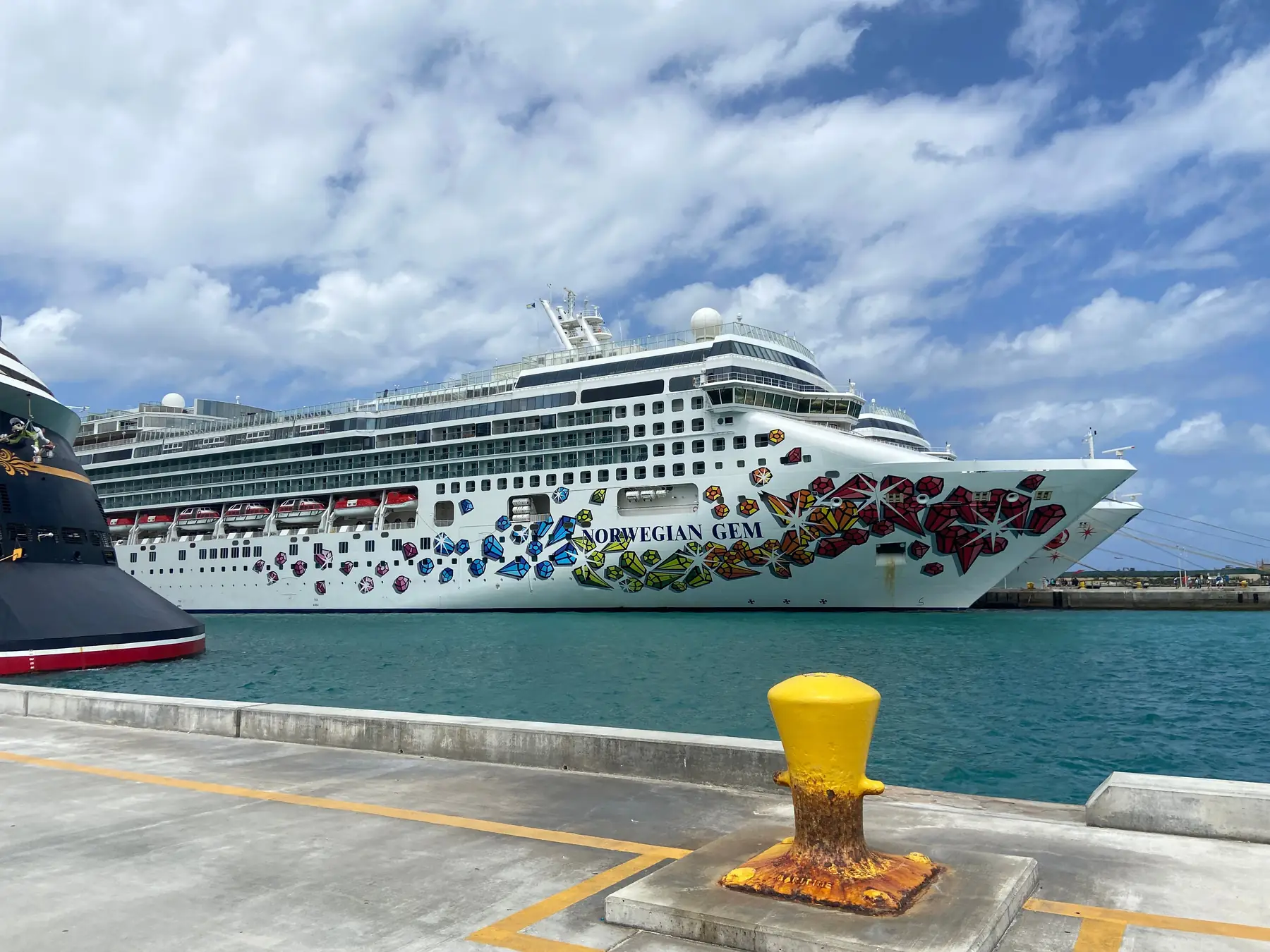Norwegian Gem cruise ship docked at Nassau Cruise Port under a bright blue sky.