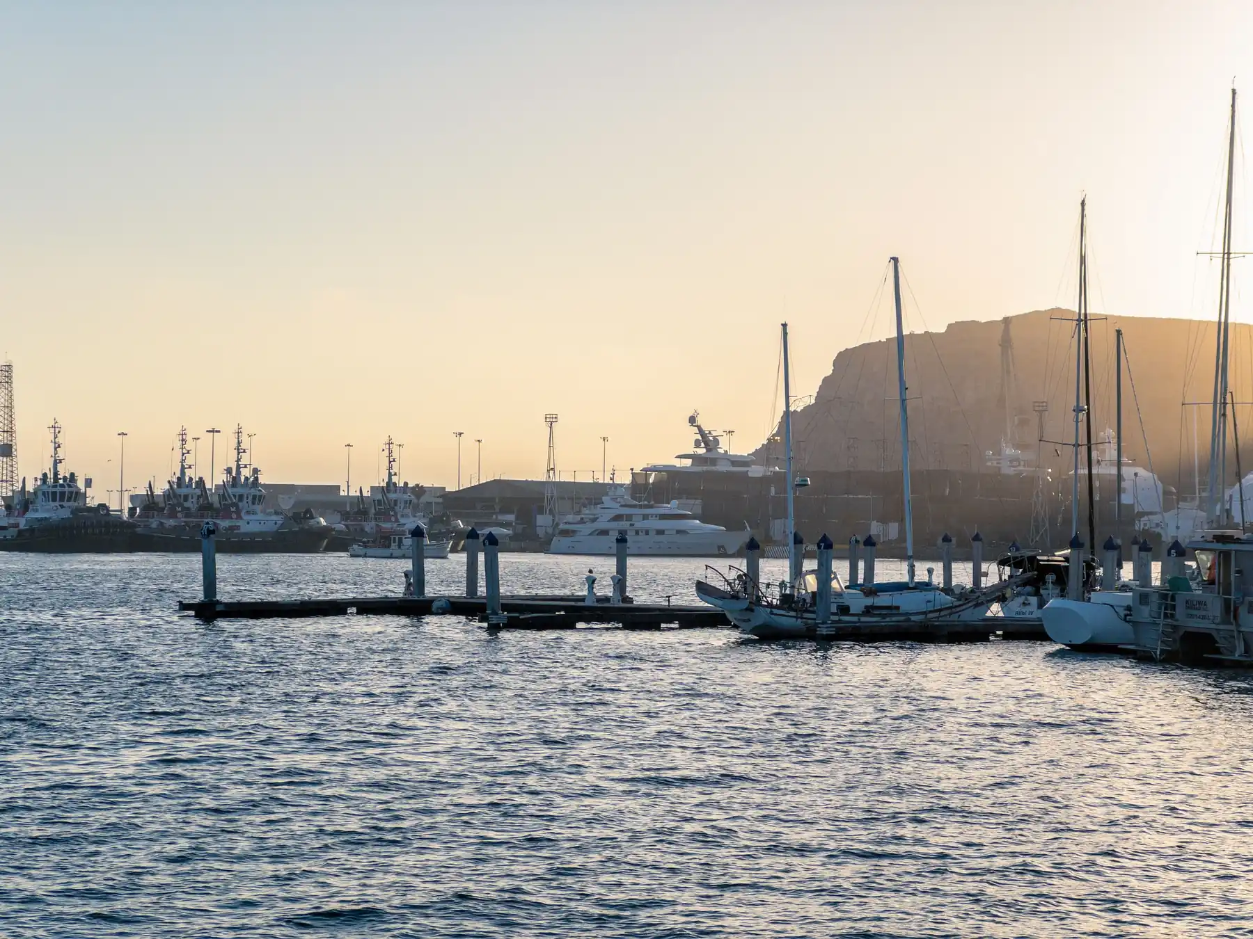 Boats in Ensenada harbor beneath a colorful sunset sky.