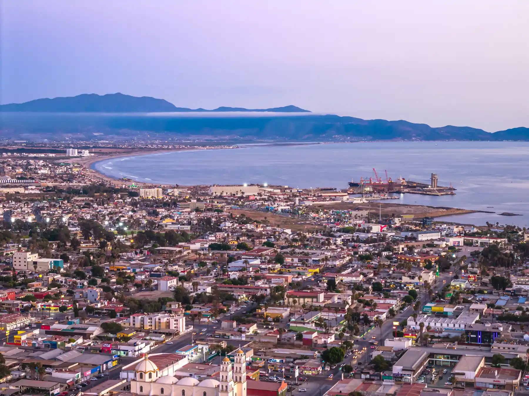 Aerial view of Ensenada's cityscape, port, and Pacific coastline.