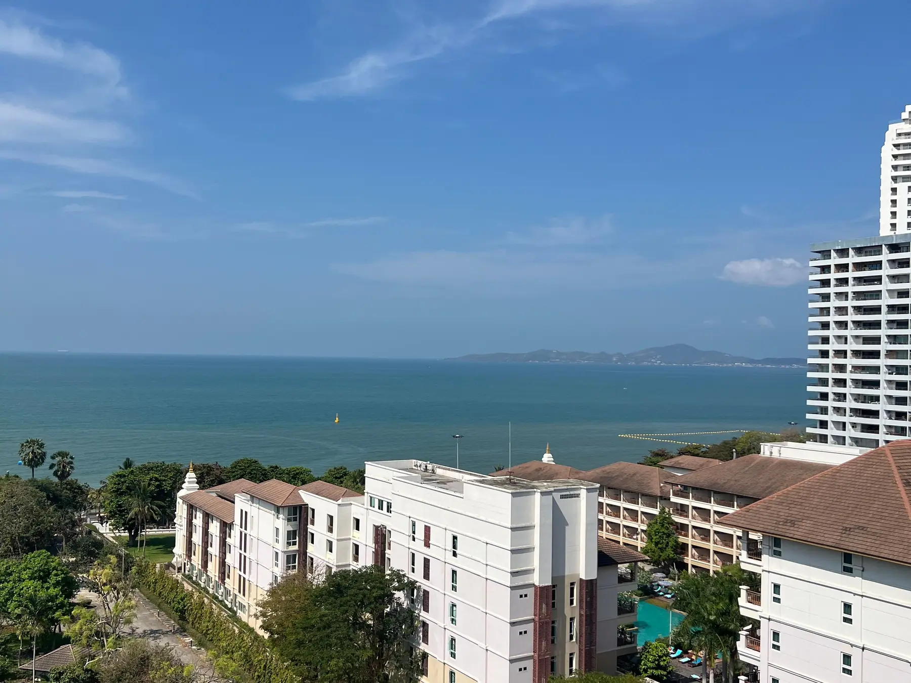 Aerial view of Pattaya's coastline, buildings, and tropical greenery.