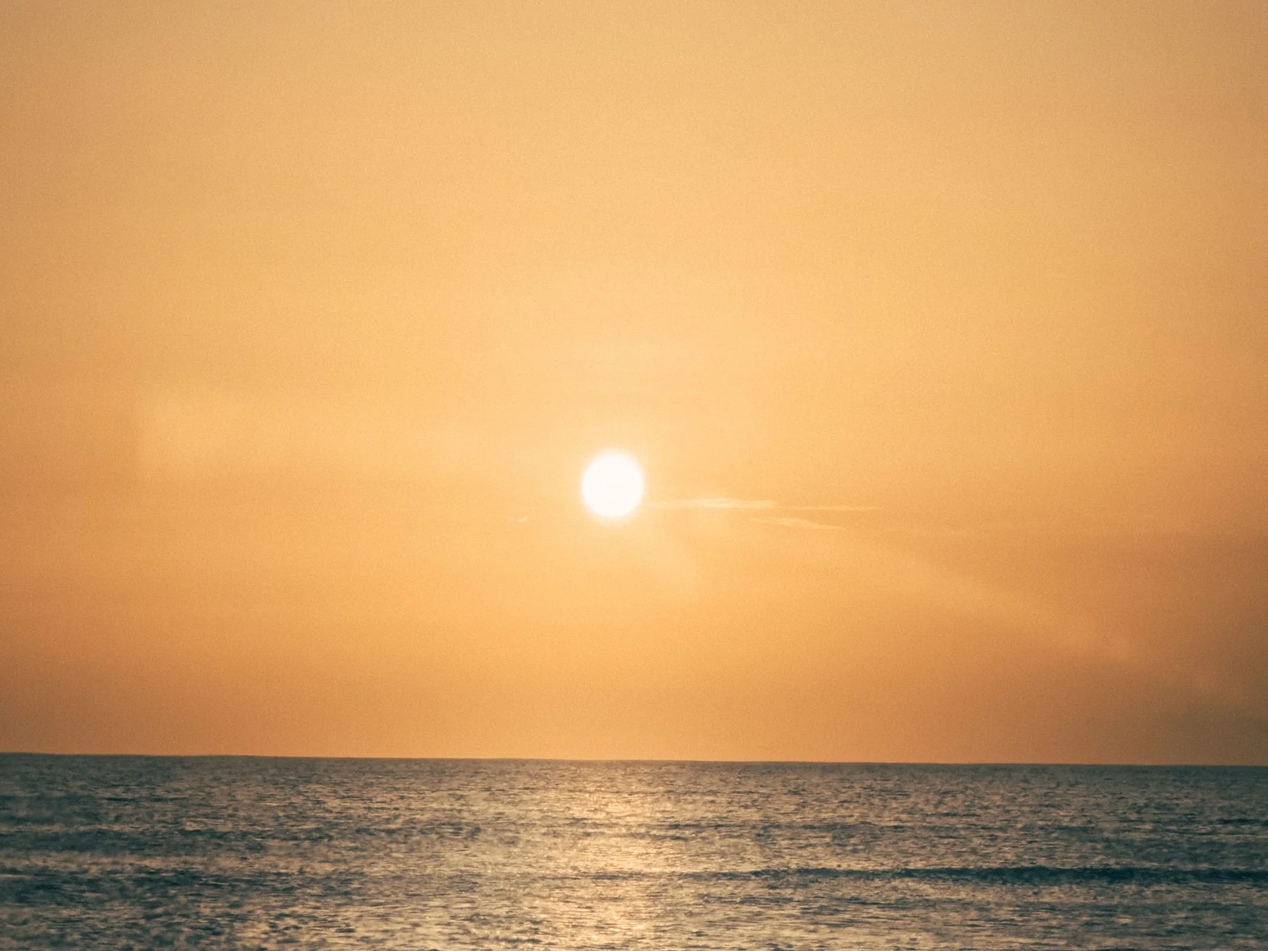 Orange sunset reflected on calm Caribbean water in Oranjestad, Aruba.