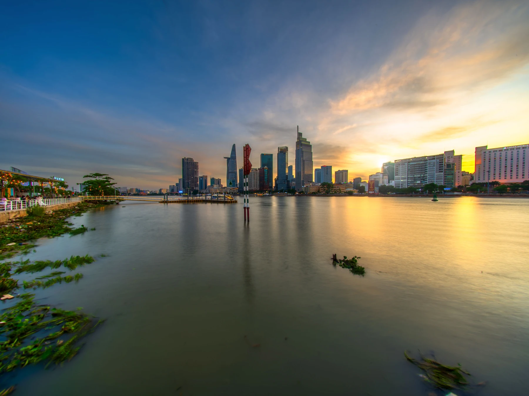 Ho Chi Minh City skyline and the Saigon River beneath a colorful sunset.