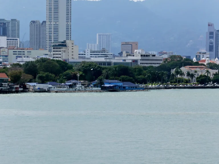 Boat cruising past George Town's waterfront skyline in Penang, Malaysia.