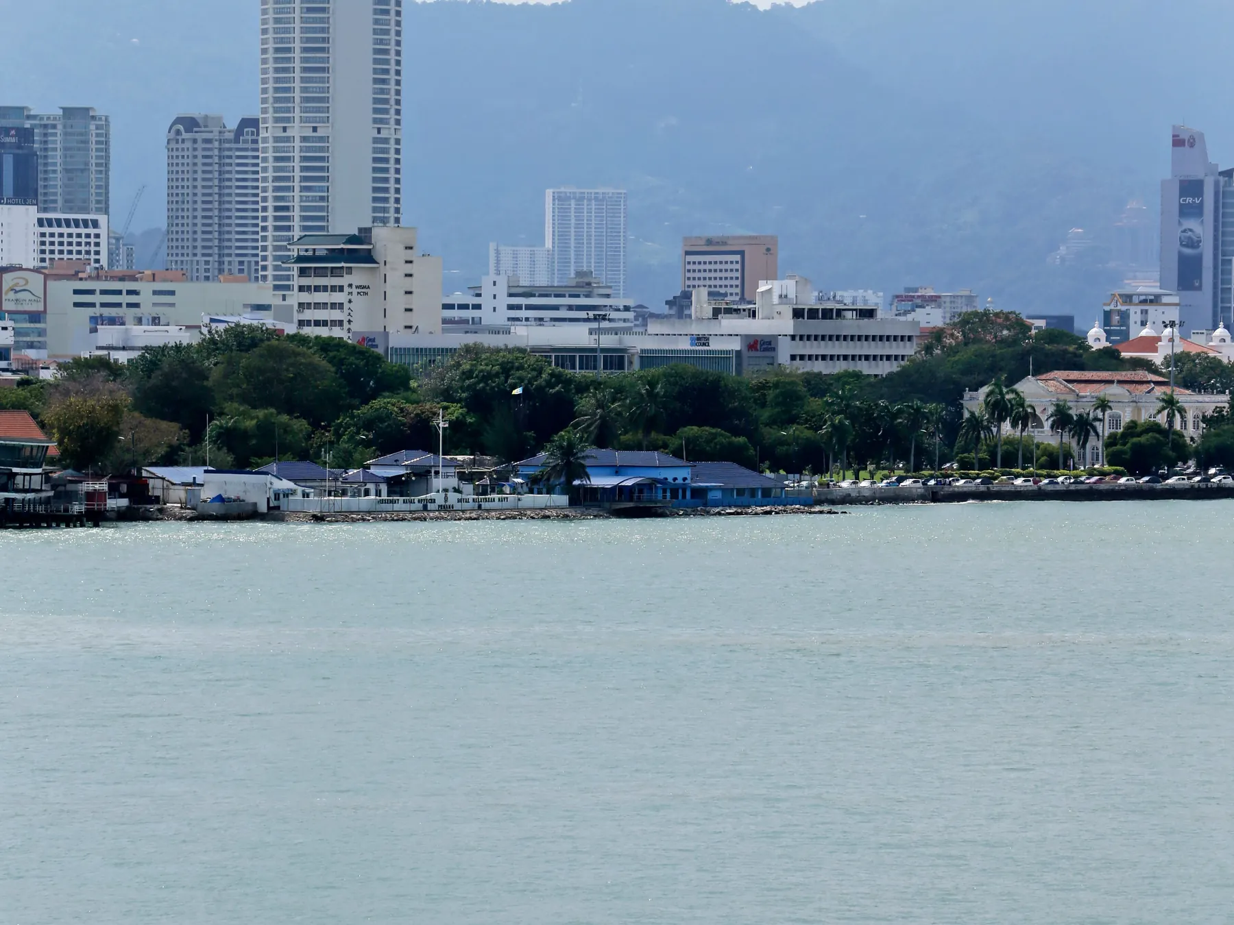 Boat cruising past George Town's waterfront skyline in Penang, Malaysia.