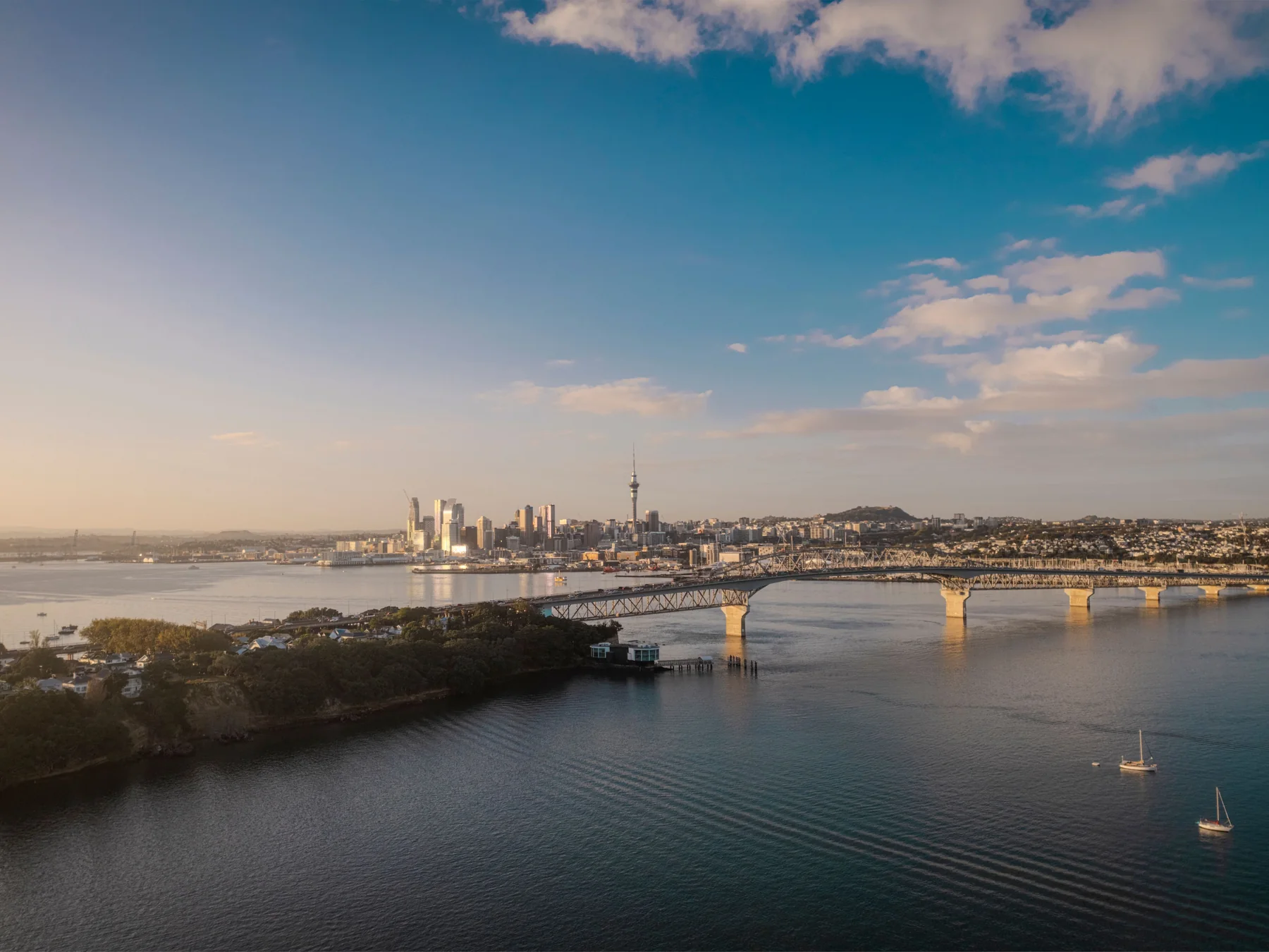 Aerial view of Auckland's skyline and Harbour Bridge at sunset.