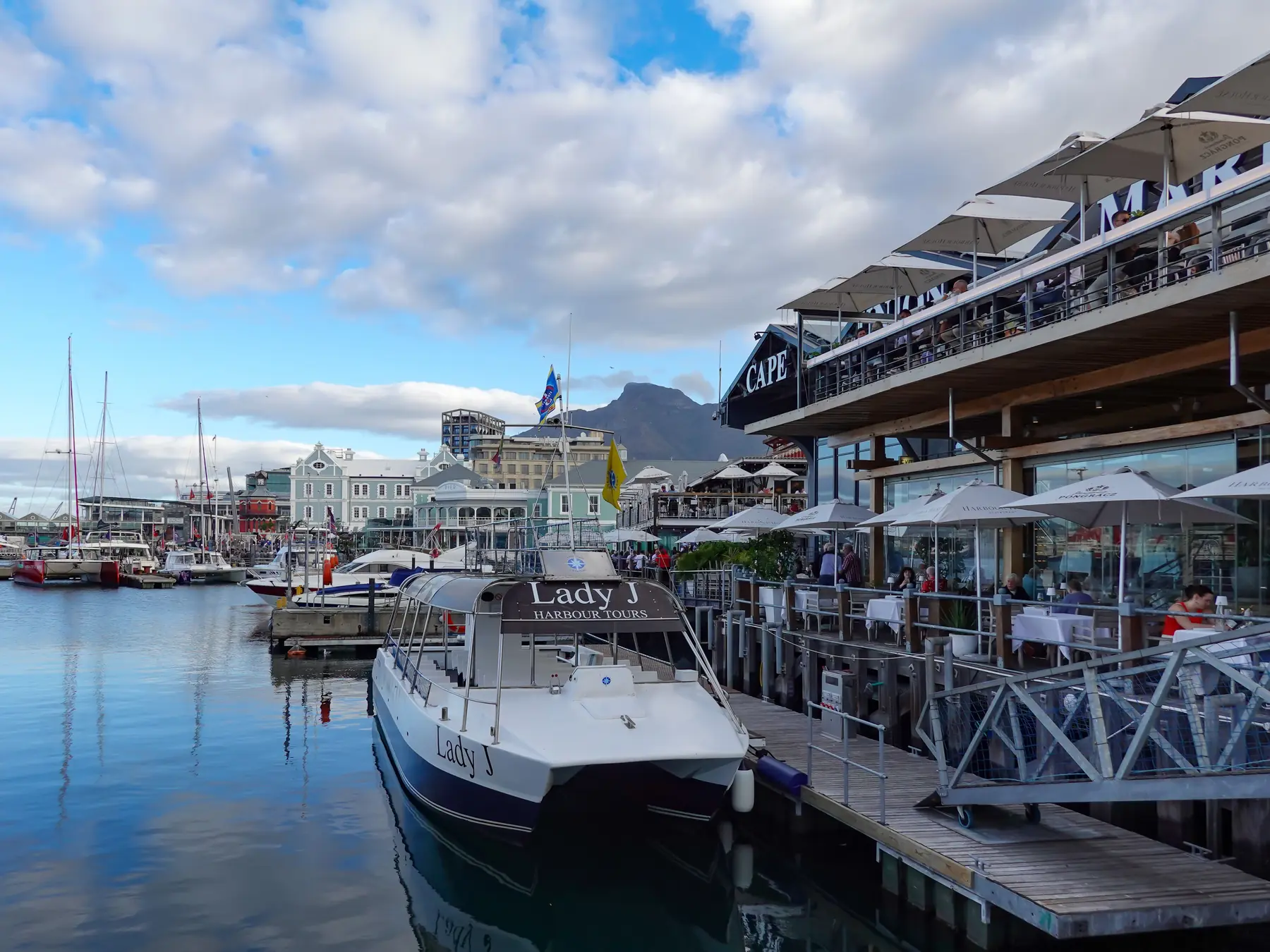 Boats and waterfront dining beside Cape Town's V&A Waterfront harbor.