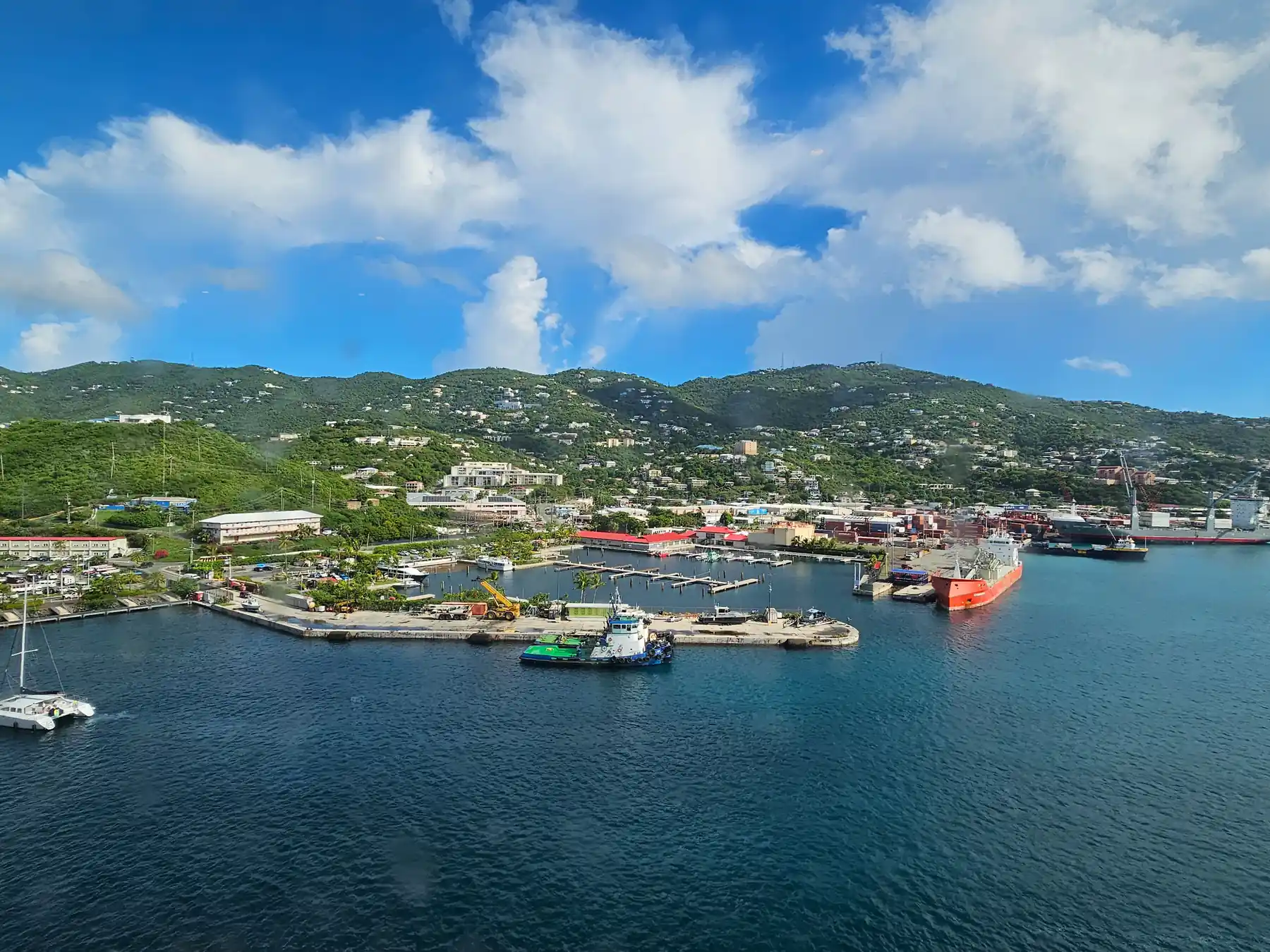 Aerial view of Charlotte Amalie harbor with ships, boats, and lush hills.