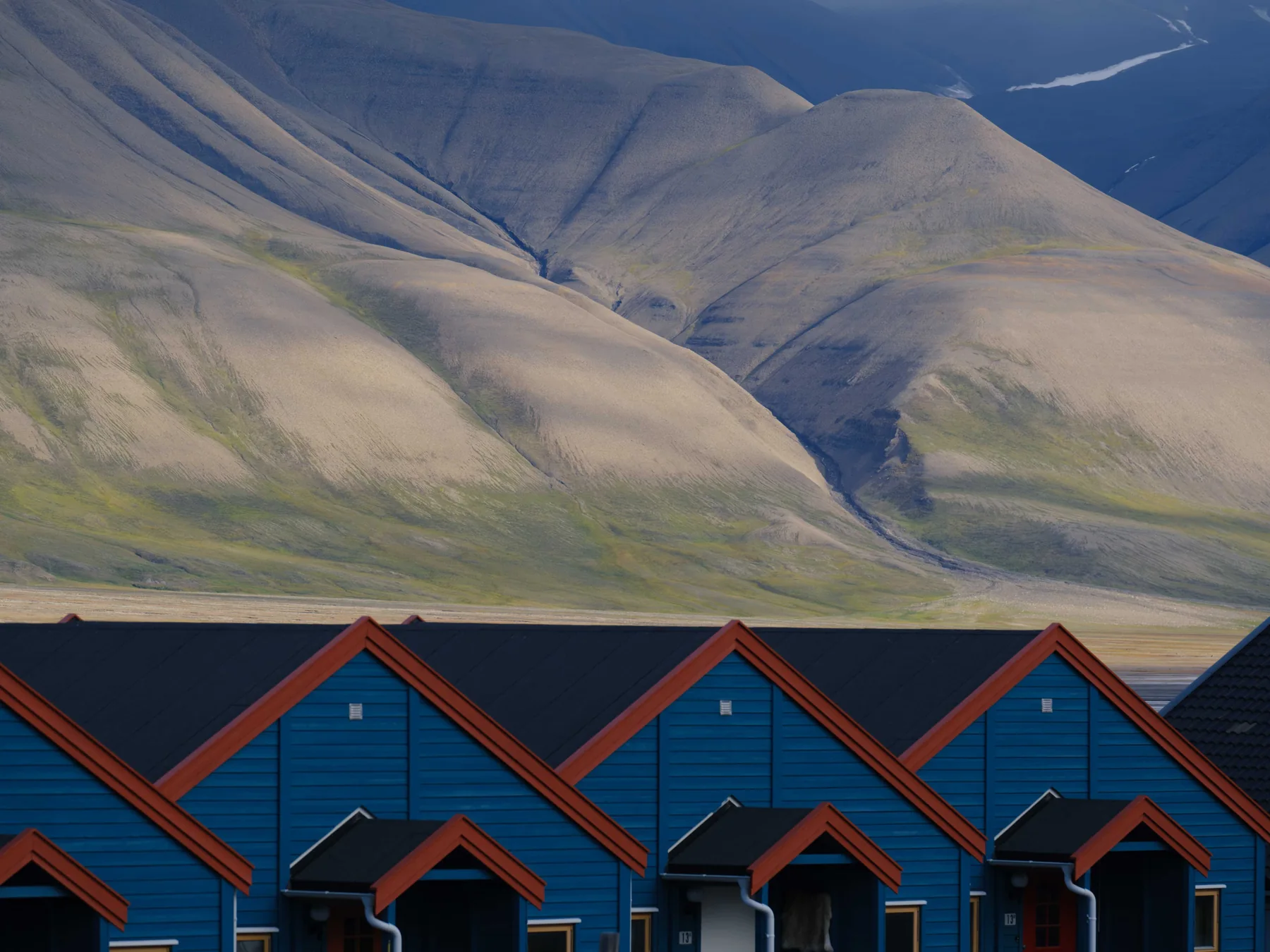 Blue cabins below rugged mountains in Longyearbyen, Svalbard.