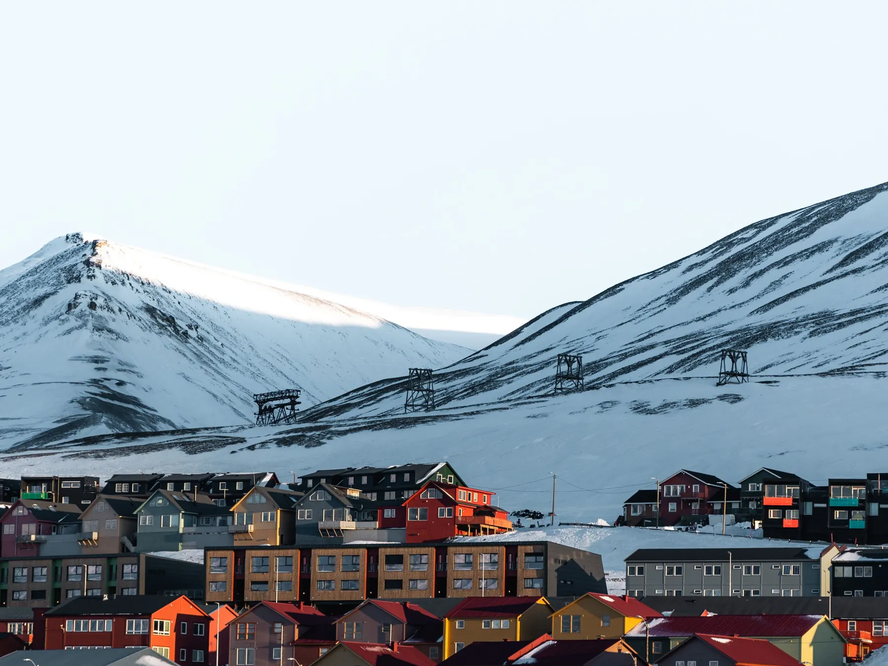 Colorful Longyearbyen houses framed by snow-covered Svalbard mountains.