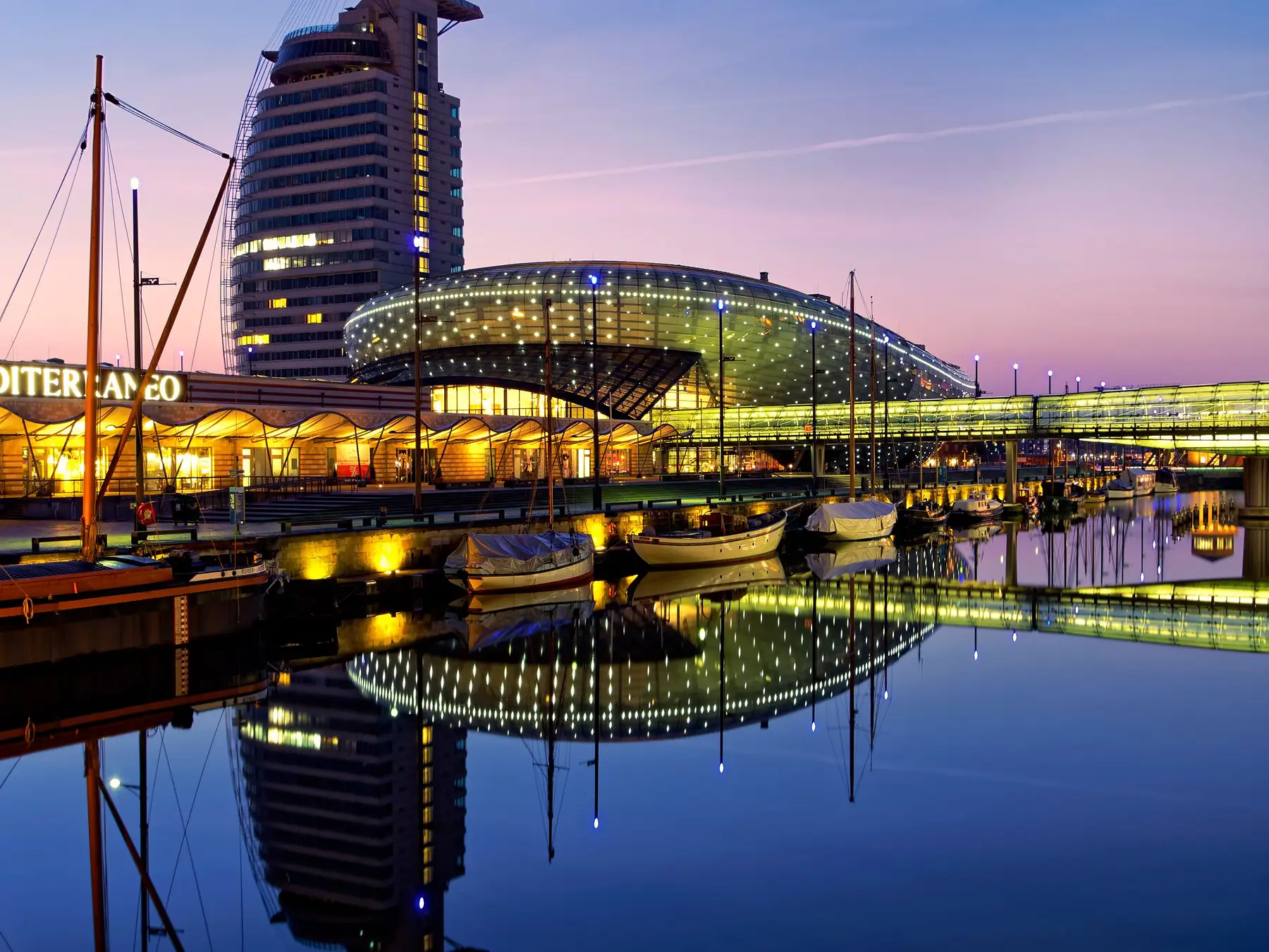 Bremerhaven marina and the Klimahaus waterfront landmark illuminated at twilight.