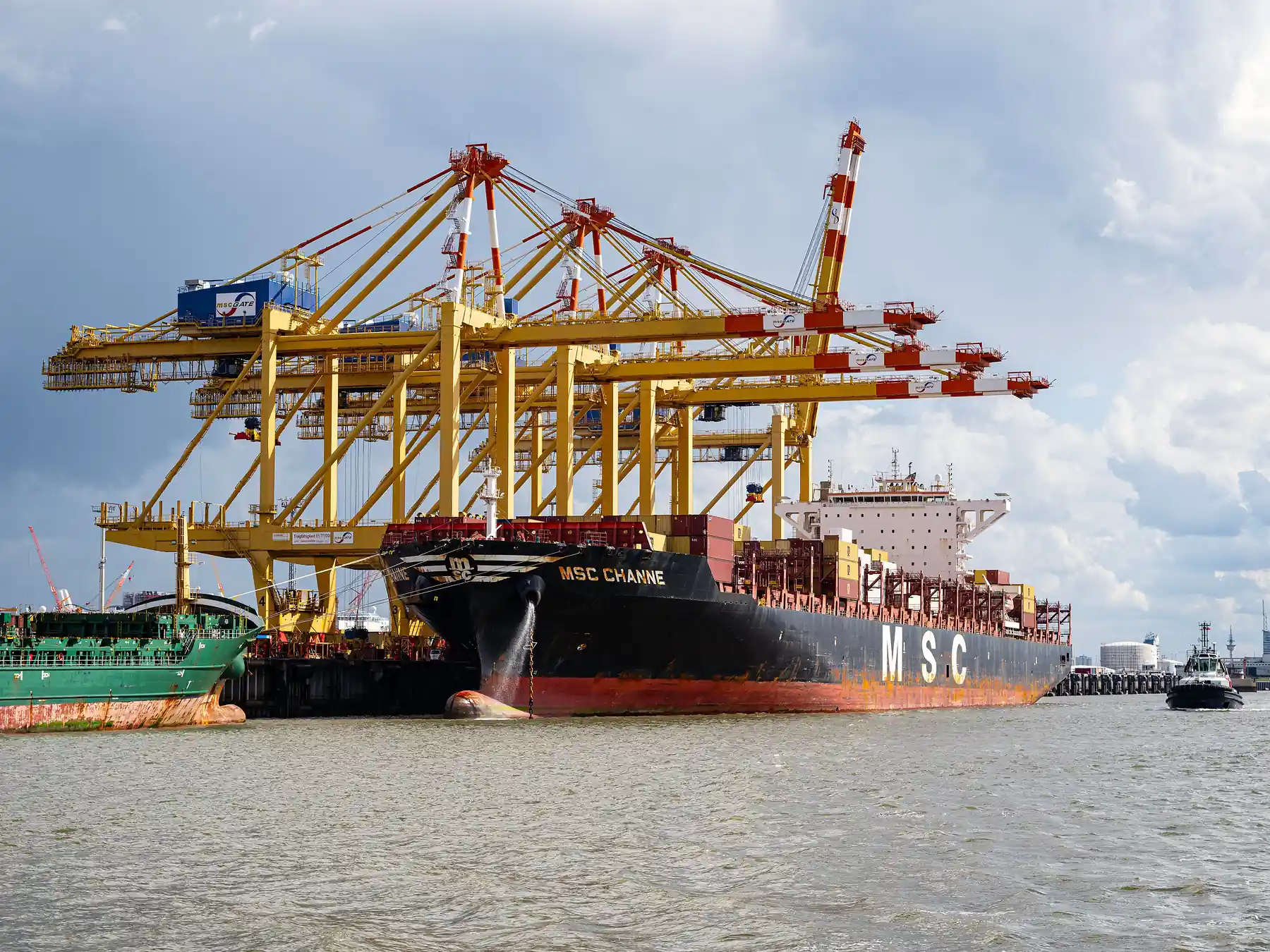 Large container ship docked beside cranes at Bremerhaven port in Germany.