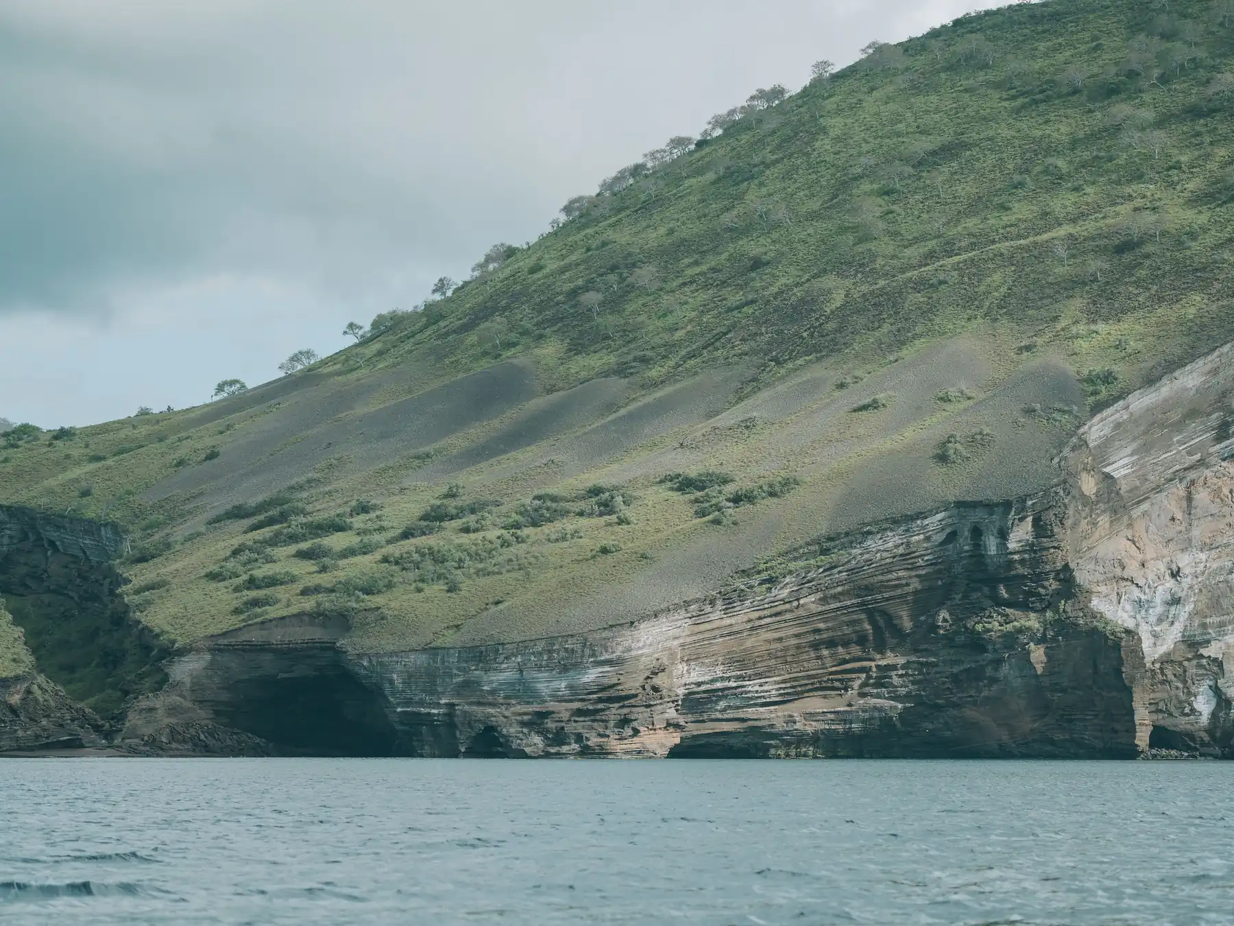 Rugged volcanic cliffs and blue ocean along the Galápagos coastline.