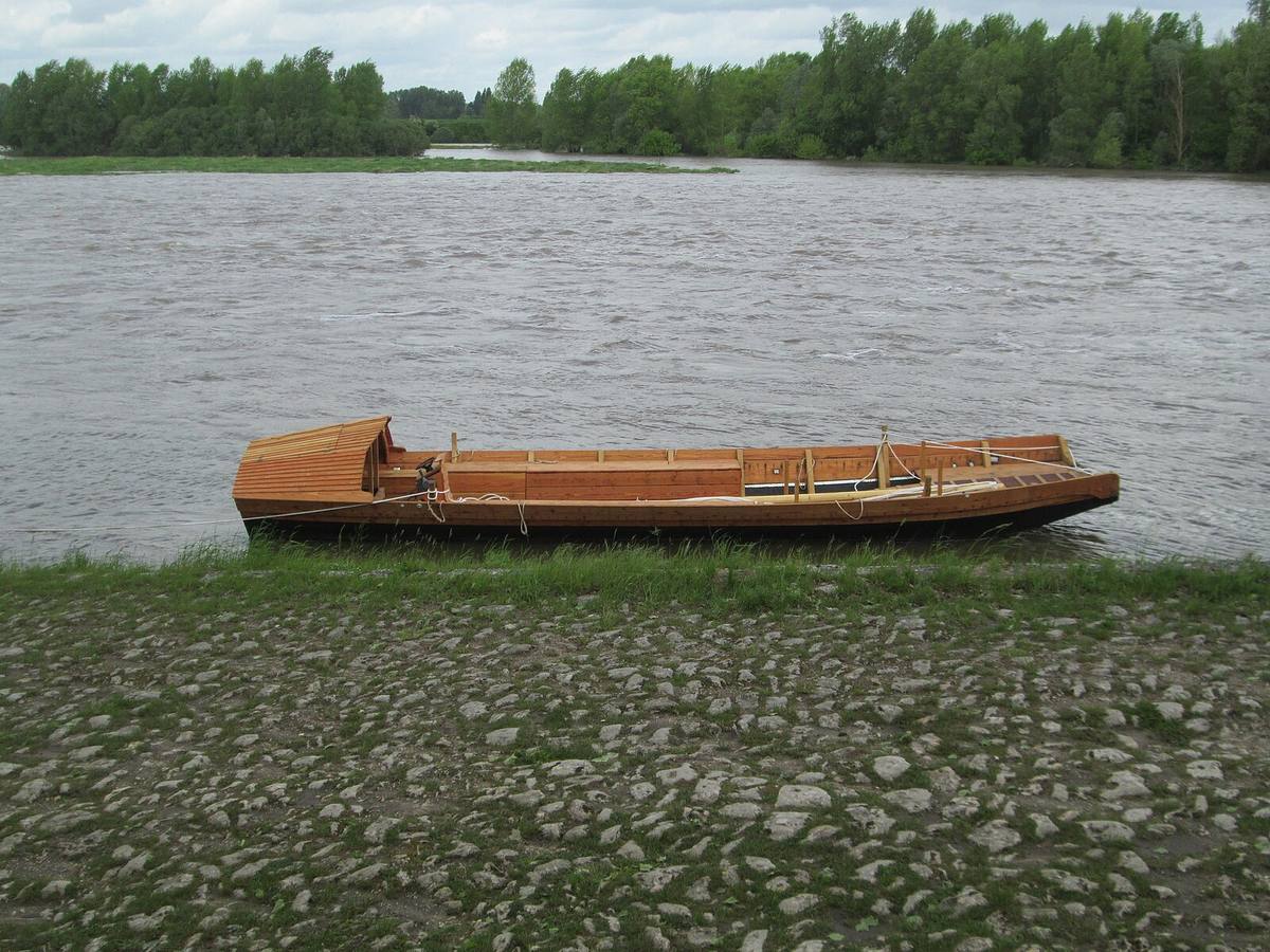 A traditional flat-bottomed boat rests on a calm French river