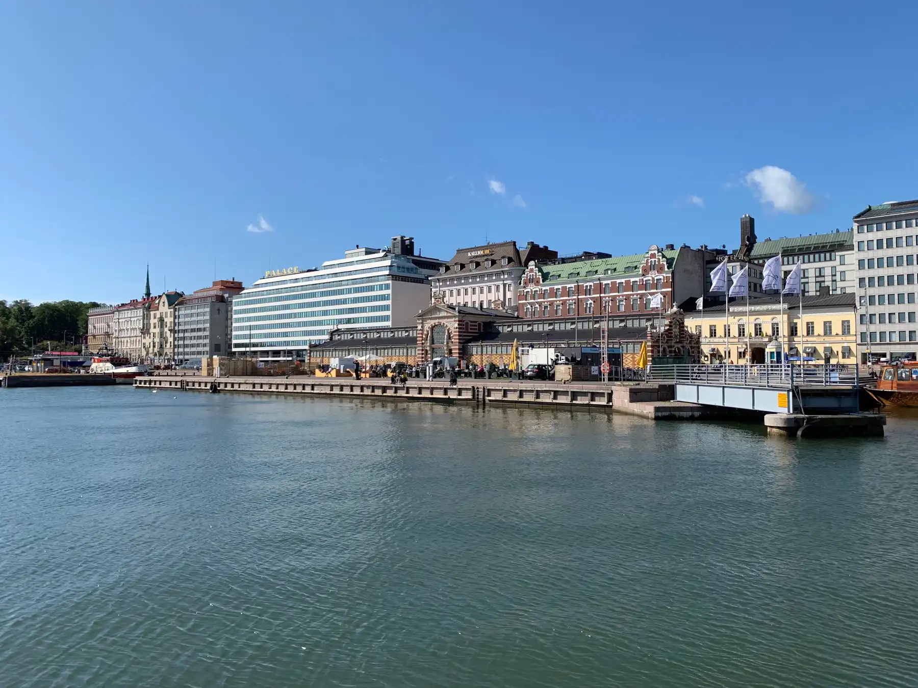 Historic and modern buildings lining Helsinki's harborfront under a clear blue sky.