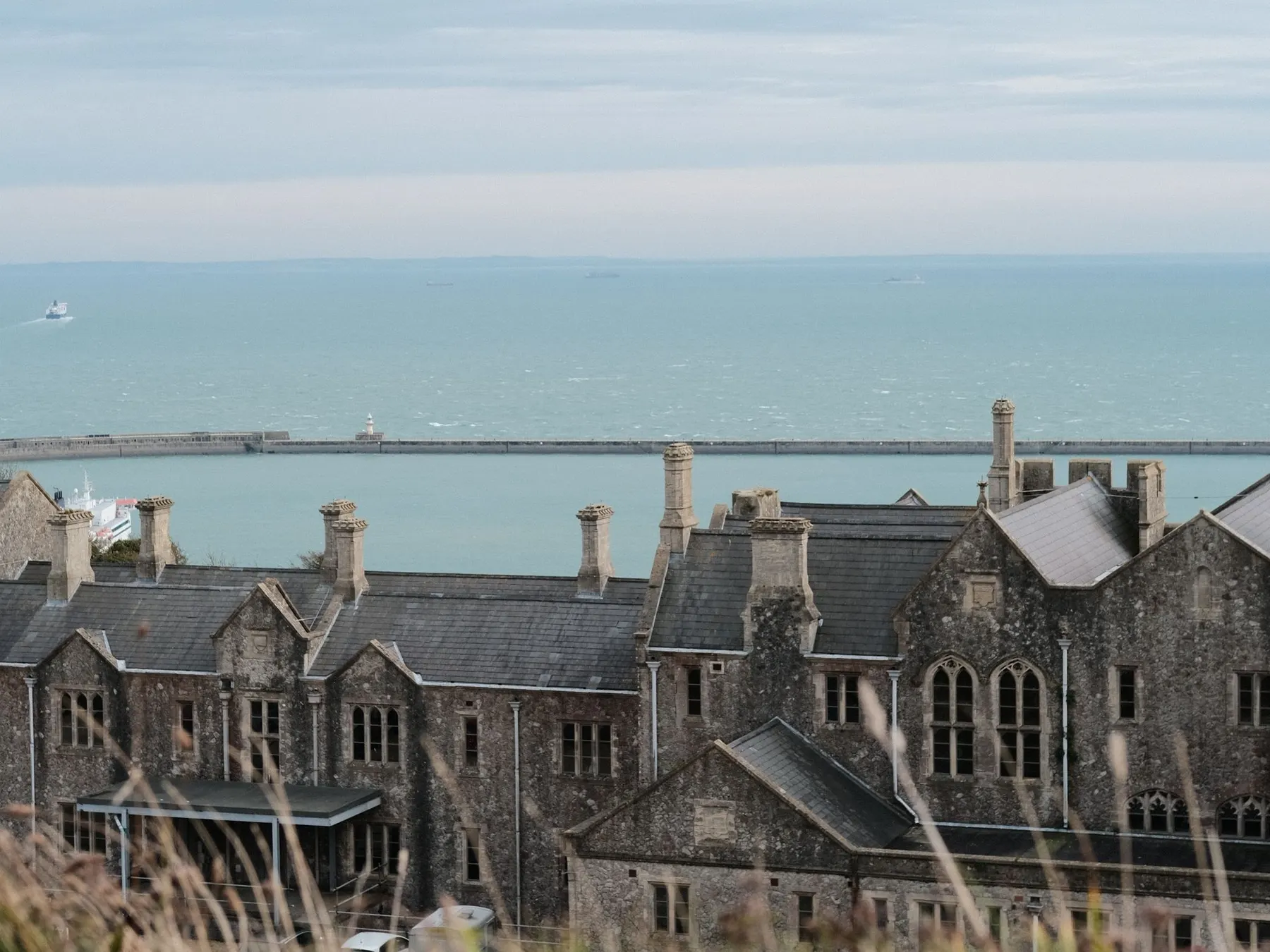 Stone buildings at Dover Castle overlooking the harbor breakwater and English Channel.