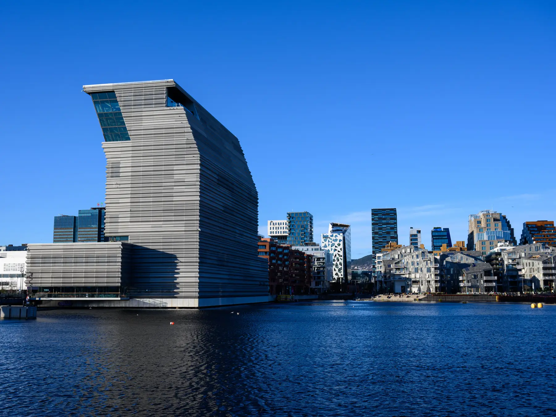 Munch Museum and the modern Bjørvika skyline beside the blue Oslo waterfront.