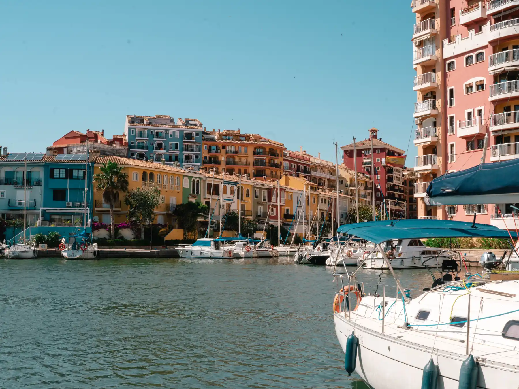 Colorful waterfront buildings and moored boats at Port Saplaya marina near Valencia.
