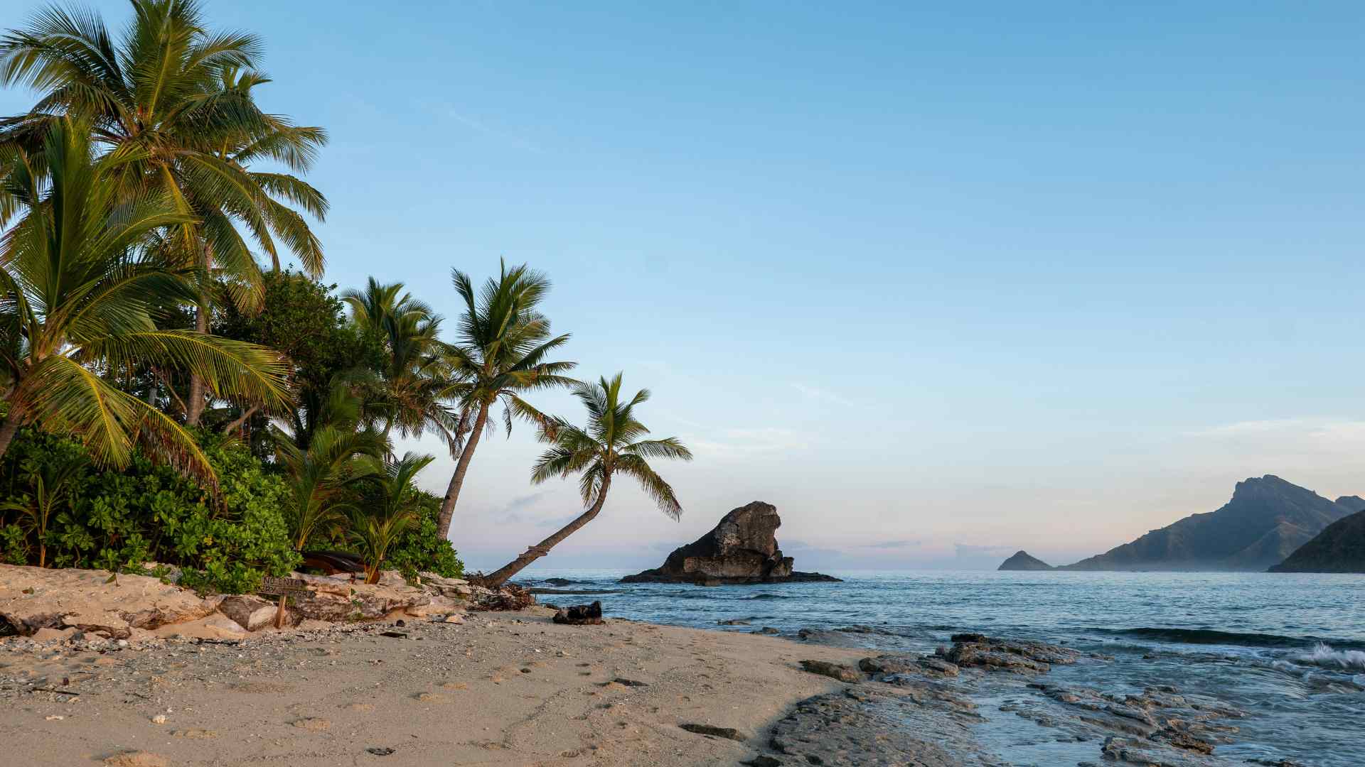 Palm-fringed beach with offshore islands in clear water