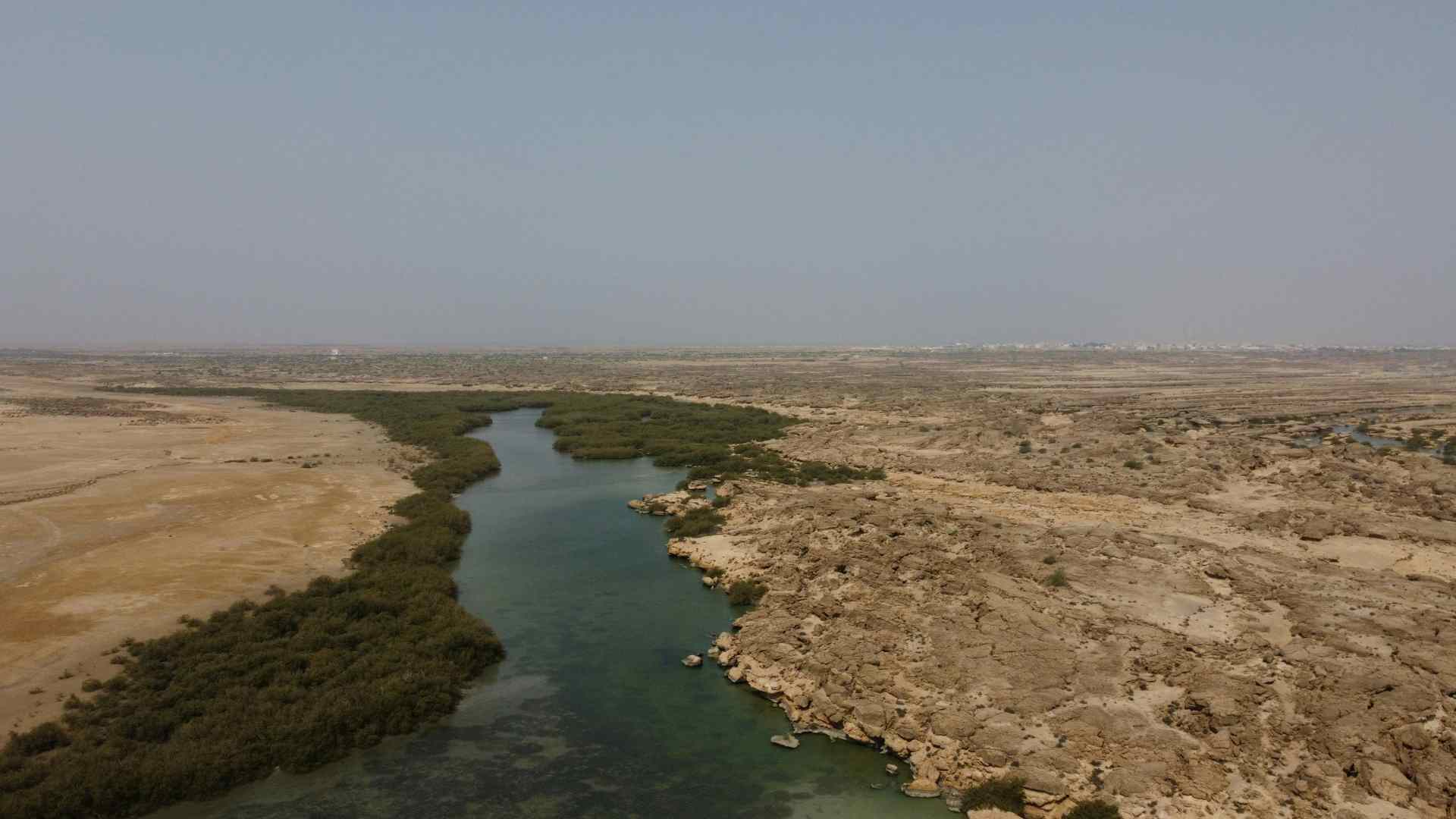 Desert wetland channel winding through a barren landscape