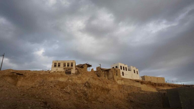 Old stone buildings beneath storm clouds near Al Wajh