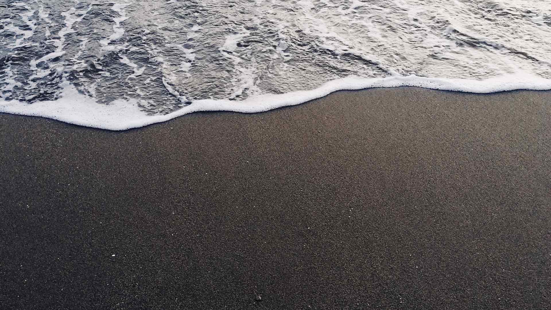 Foamy waves washing onto a dark beach near Almeria