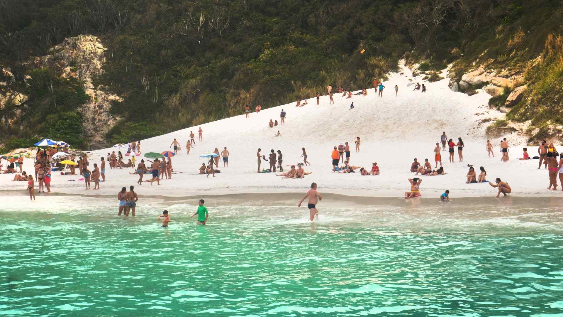 Visitors swimming at a white sand beach in Arraial do Cabo