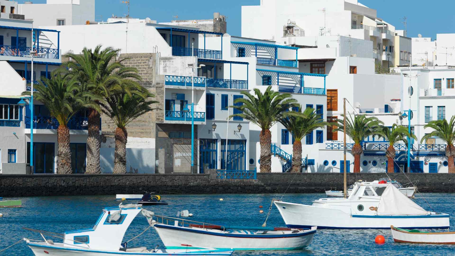 White-and-blue waterfront buildings beside boats in Arrecife