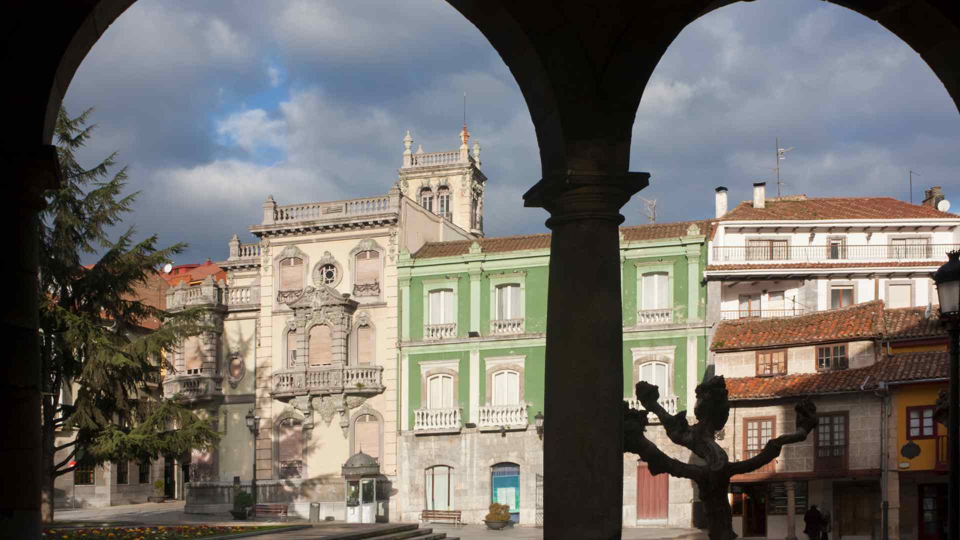 Aviles City Hall viewed through a shaded stone arcade