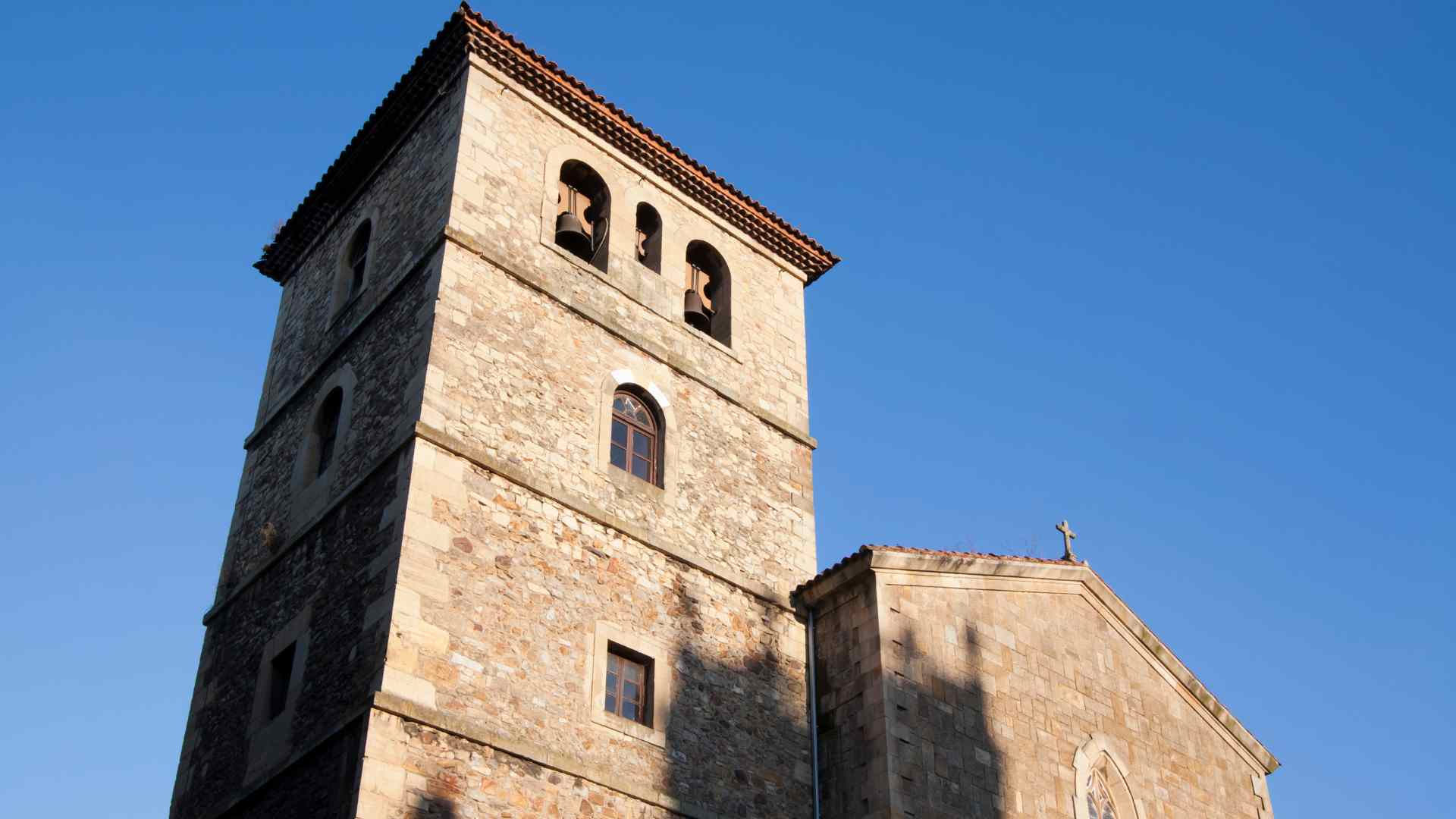 Stone bell tower beneath a clear sky in Aviles, Spain