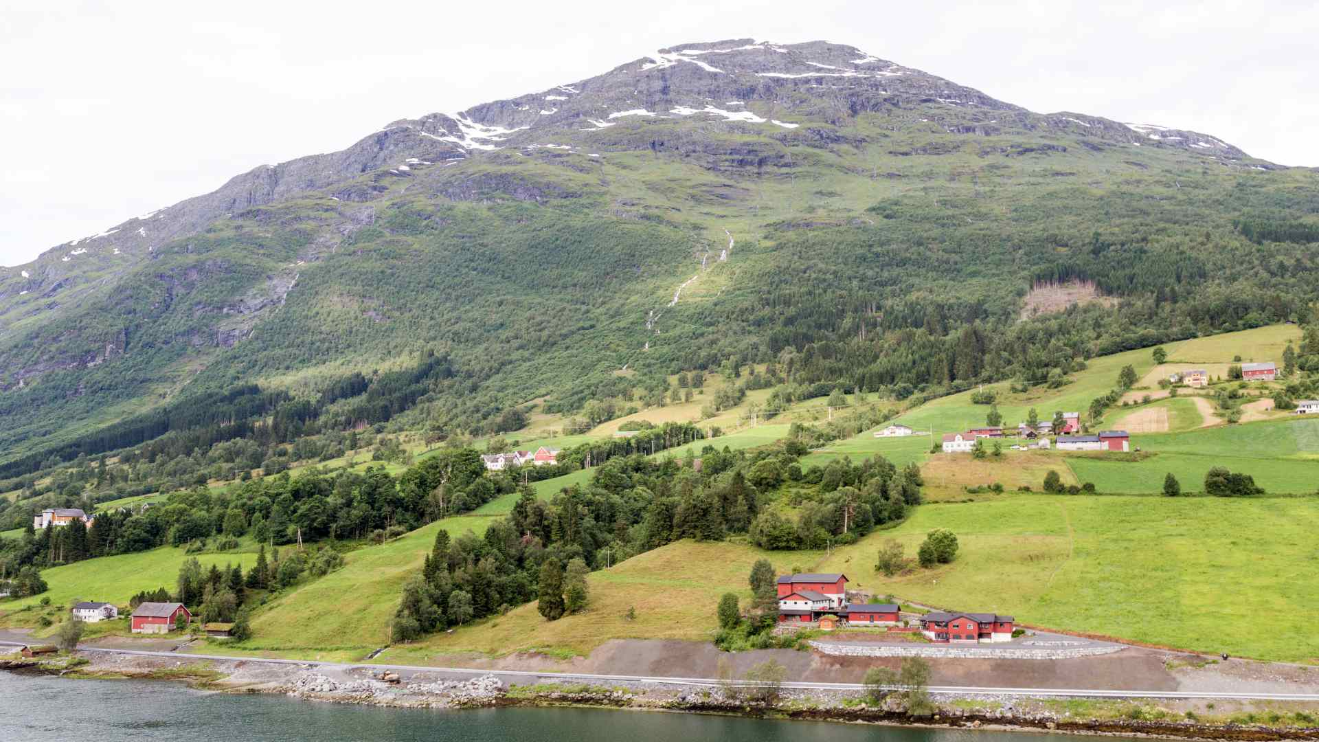 Green farmland and mountain slopes beside a fjord
