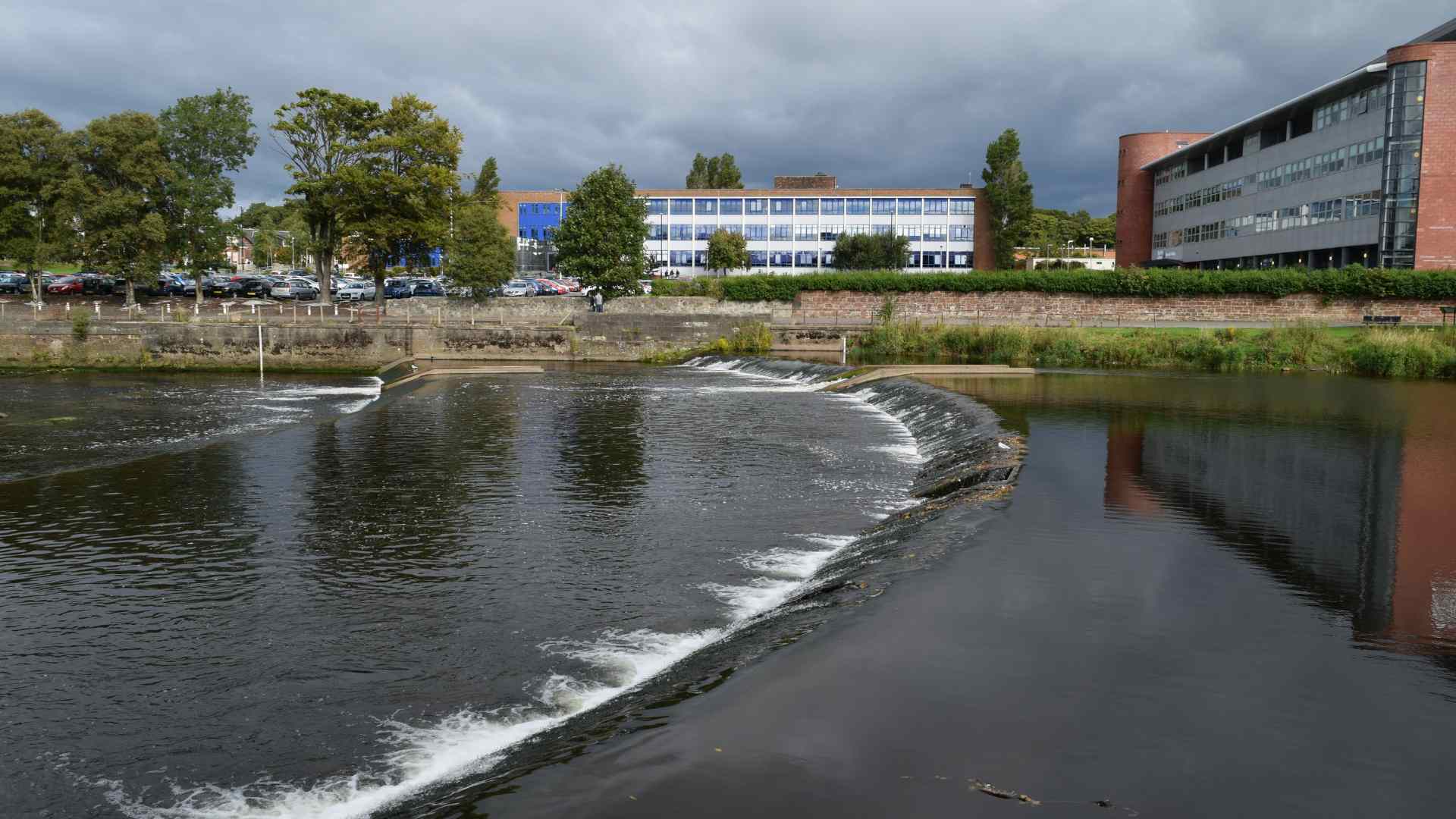 Curved river weir and parkland in Ayr, Scotland
