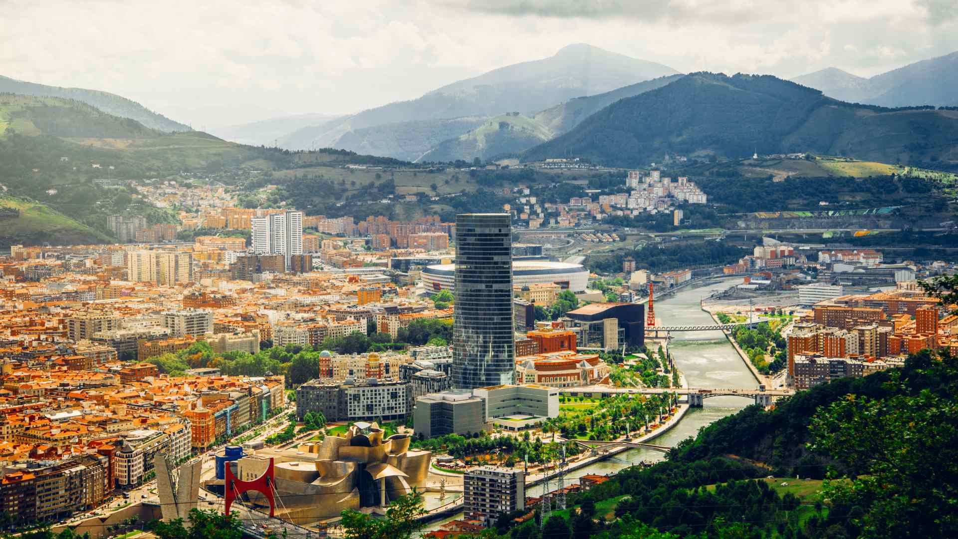 Aerial panorama of Bilbao surrounded by green Basque hills
