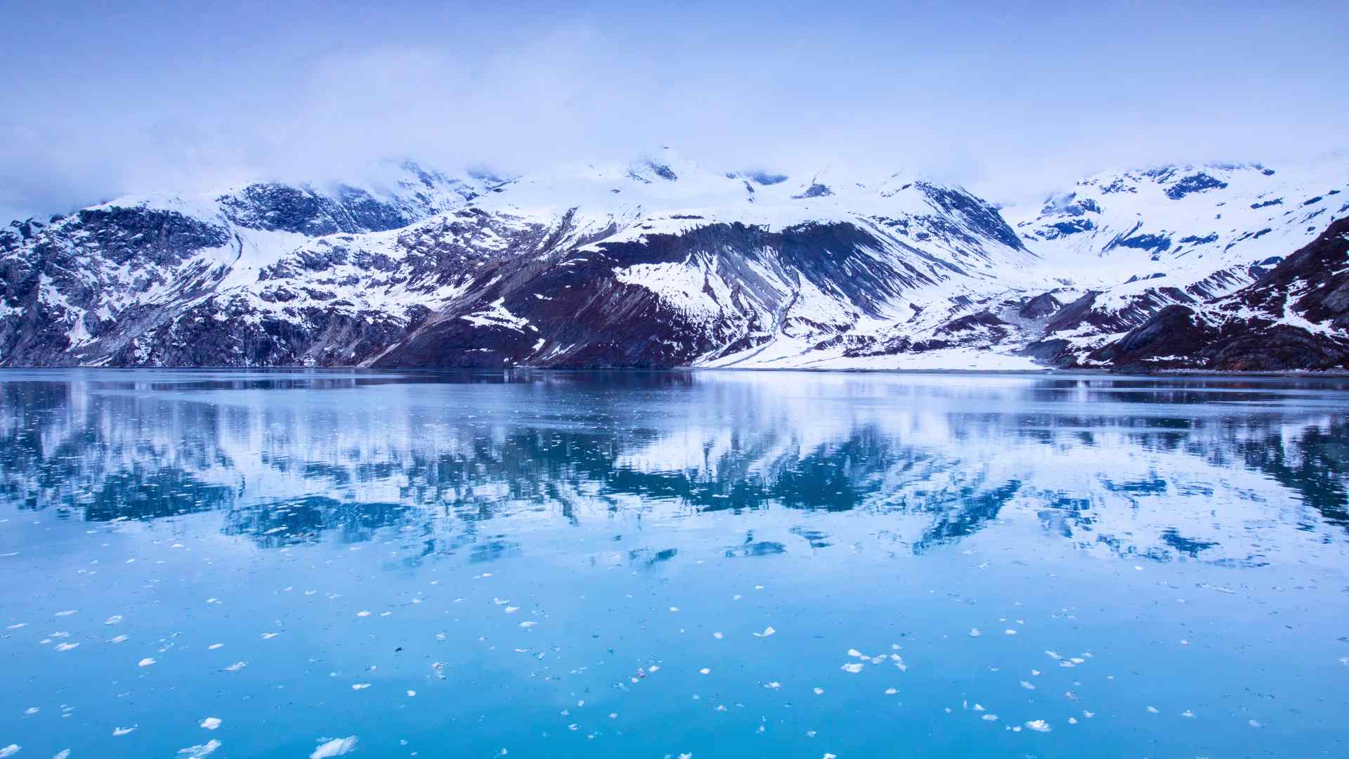Snow-covered mountains reflected in calm Glacier Bay waters