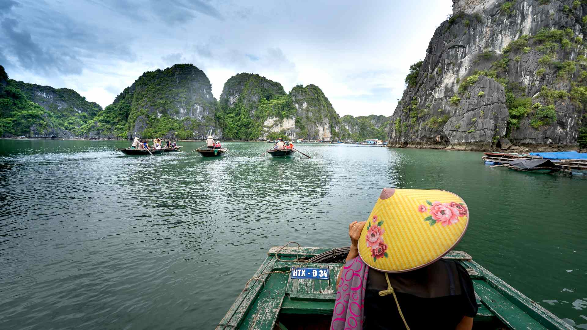 Traveler in a conical hat boating through Ha Long Bay